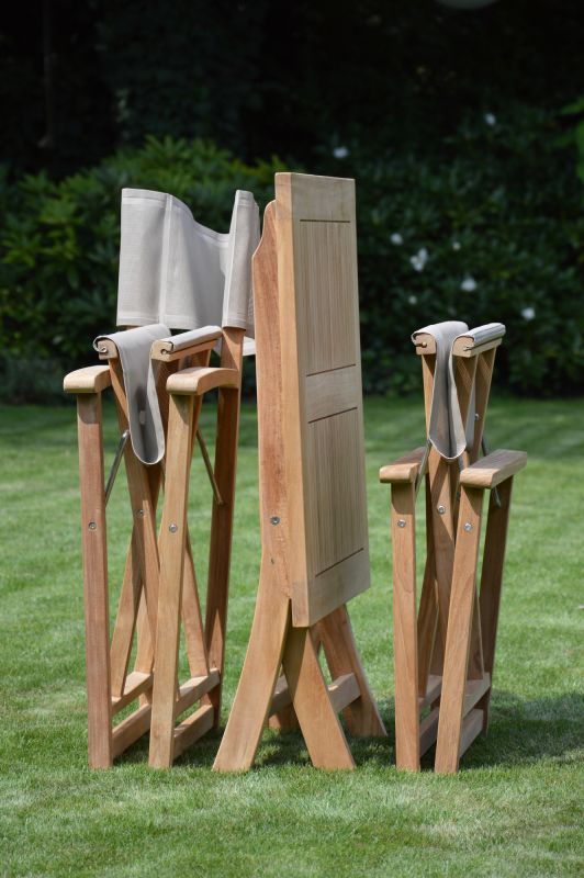 Zusammengeklappter Urban Regiestuhl von Jan Kurtz mit taupefarbenem Bezug auf Rasen, Gartenmöbel aus Teakholz.