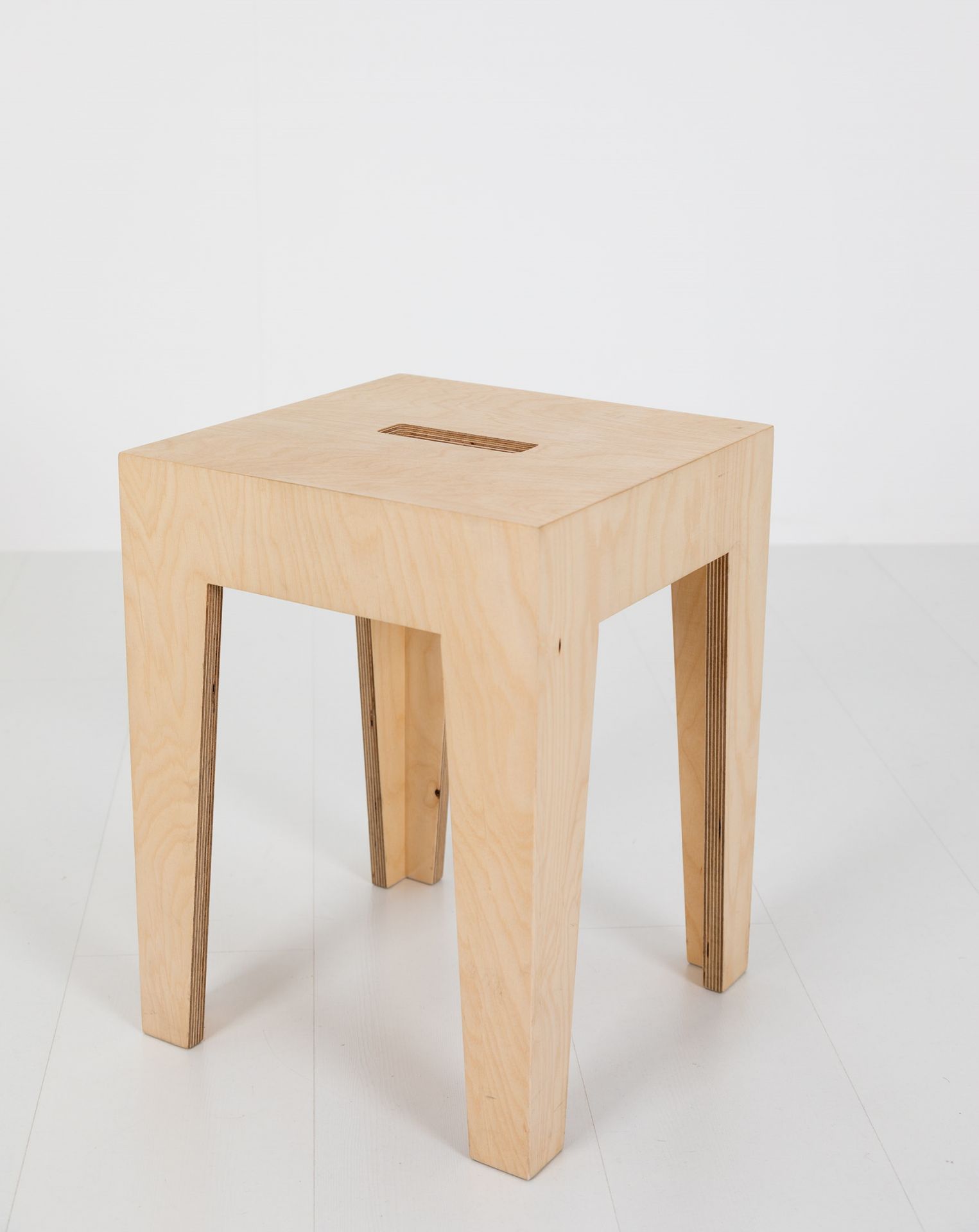 HENRIK Hocker aus hellem Holz, quadratisch mit Schlitz im Sitz, minimalistisches Design.