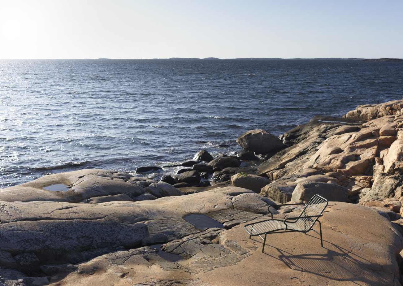 Normann Copenhagen Vig Liege im Freien auf Felsen am Meer, modernes Outdoor-Möbel Design.