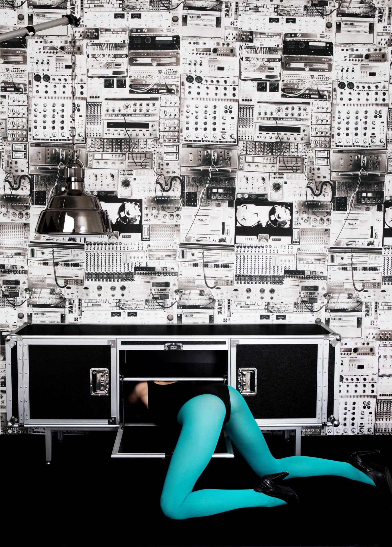 Total Sideboard schwarz von Moroso Diesel mit Person in türkiser Strumpfhose, die in das Möbelstück kriecht.