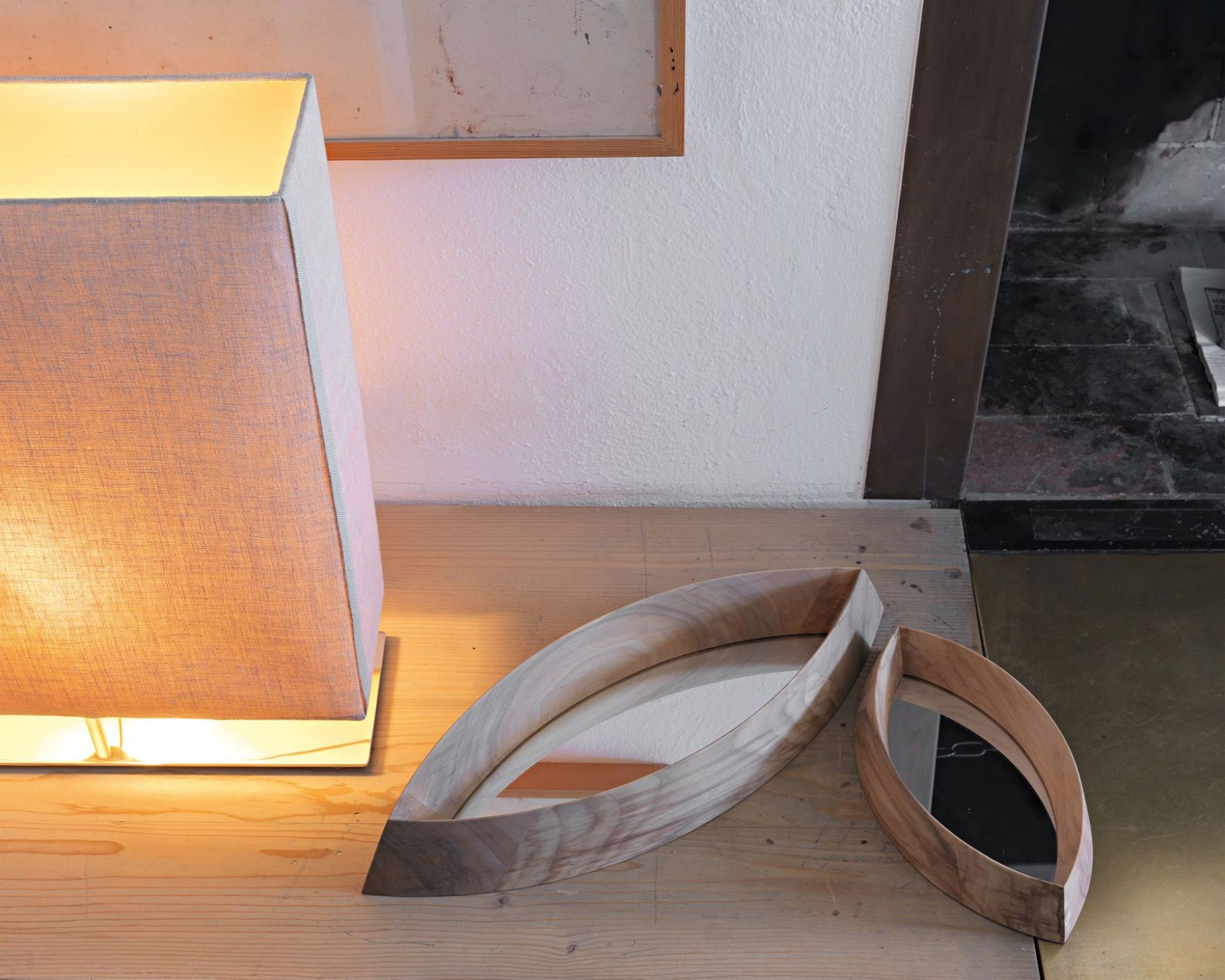 Zwei Mamanonmama Spiegel mit Holzrahmen in Blattform auf einem Holztisch, neben einer Lampe.