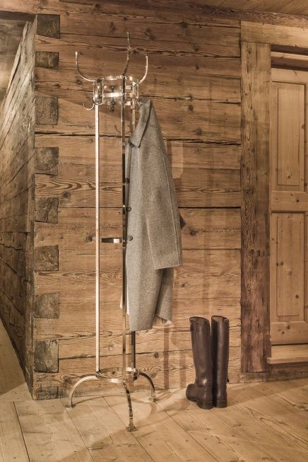 Nymphenburg Garderobenständer von ClassiCon in Schwarz mit Mantel und Stiefeln vor Holzwand.