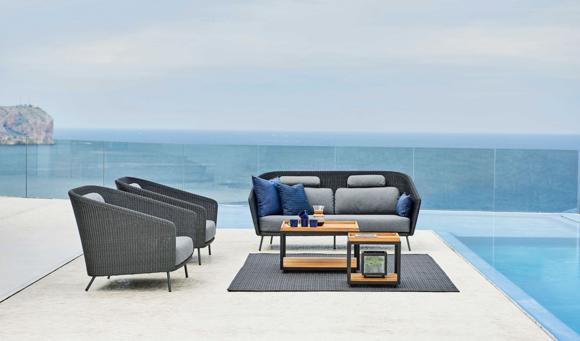 Mega Outdoor Loungesessel von Cane-Line aus Rattan mit grauen Polstern und passendem Outdoor-Sofa.