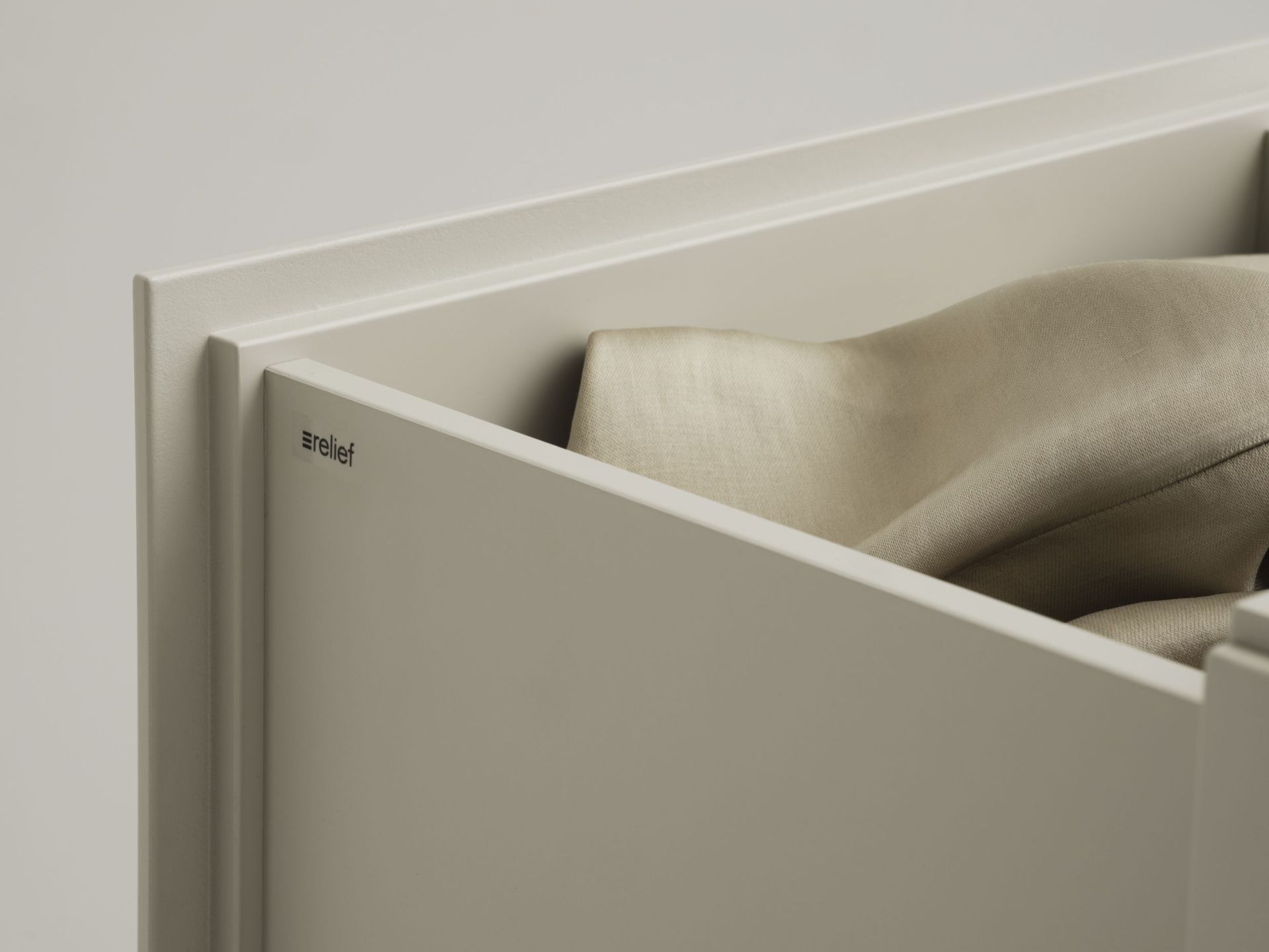 Detailaufnahme einer offenen Relief Kommode von String Furniture mit Textilien.