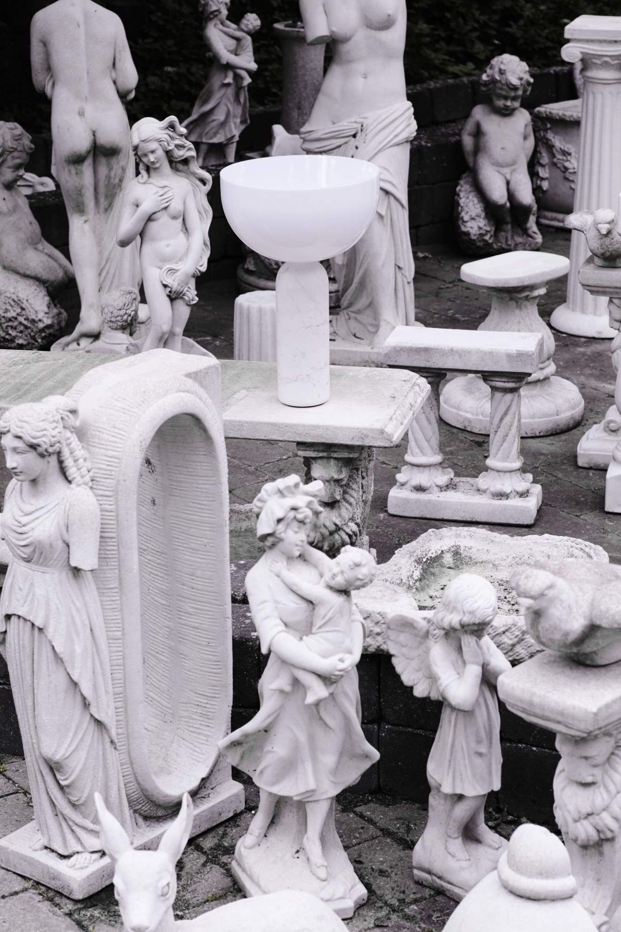 New Works Kizu Tischleuchte in Weiß, umgeben von Statuen. Moderne Lampe für stilvolle Innenbeleuchtung.