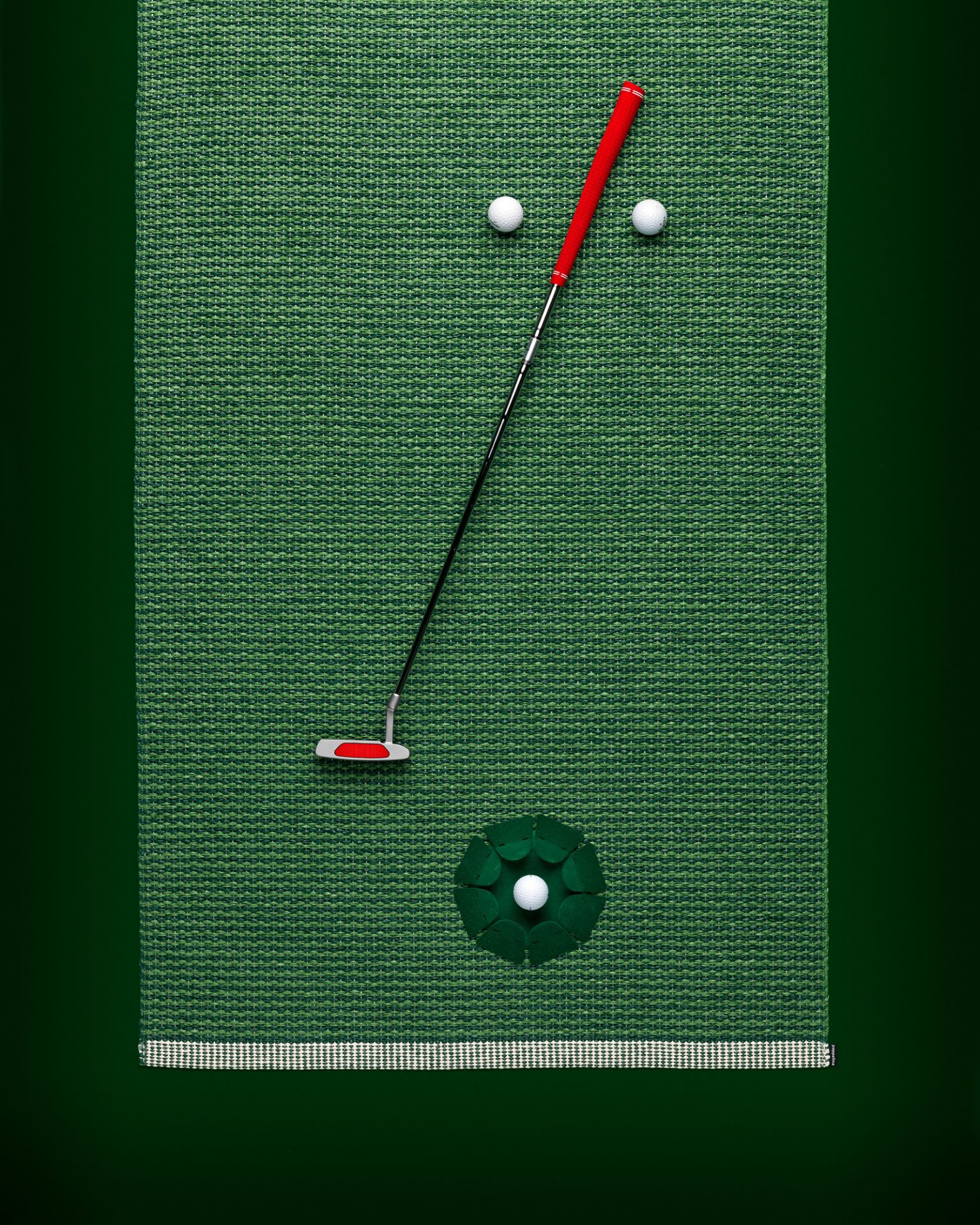 Grüner Mono Kunststoffteppich von Pappelina, 60x150 cm, mit Golfschläger und Golfbällen als Dekoration.