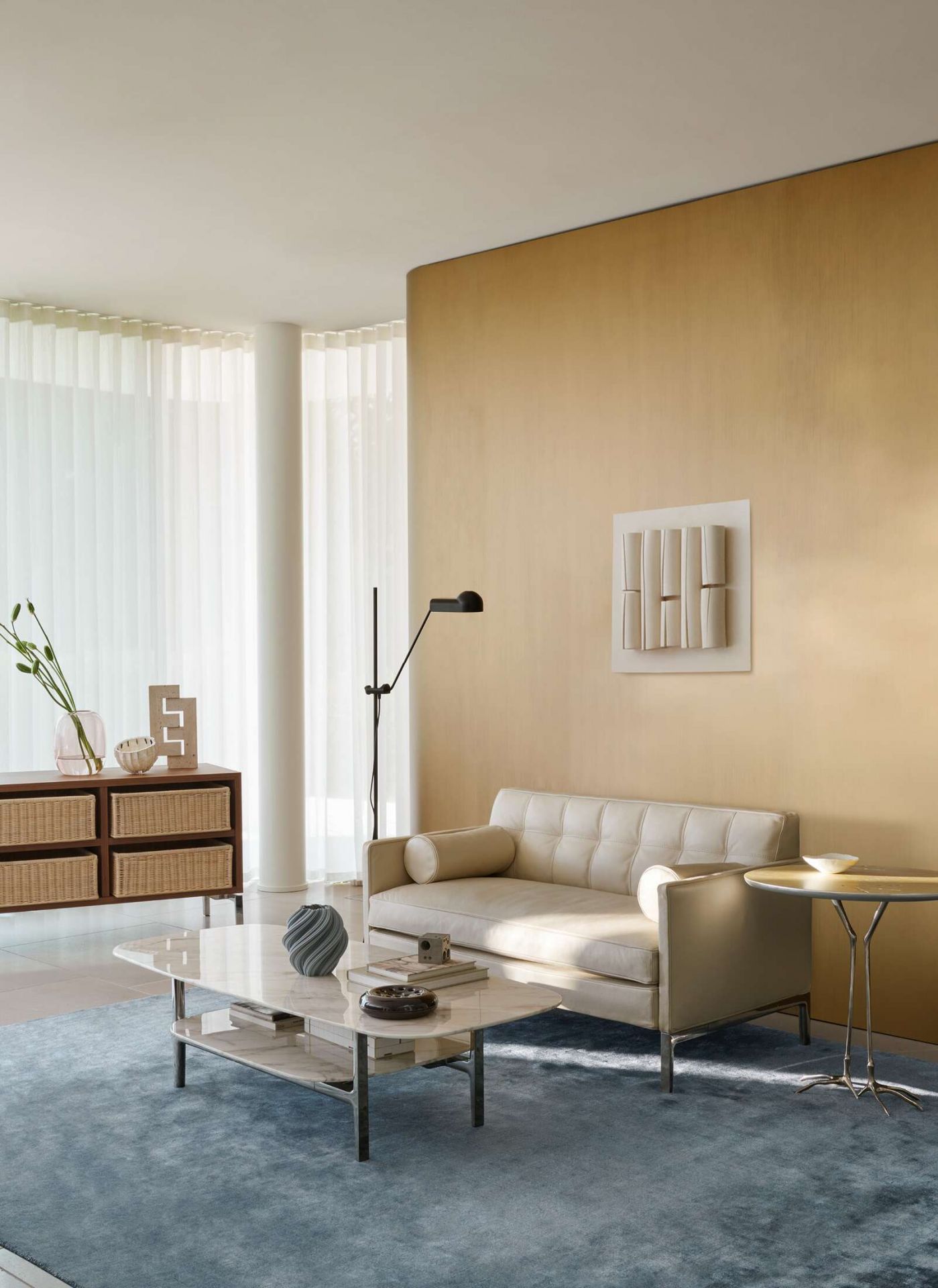 Wohnzimmer Interieur mit Cassina W50 Traccia Beistelltisch aus Marmor neben beigem Sofa und Teppich.