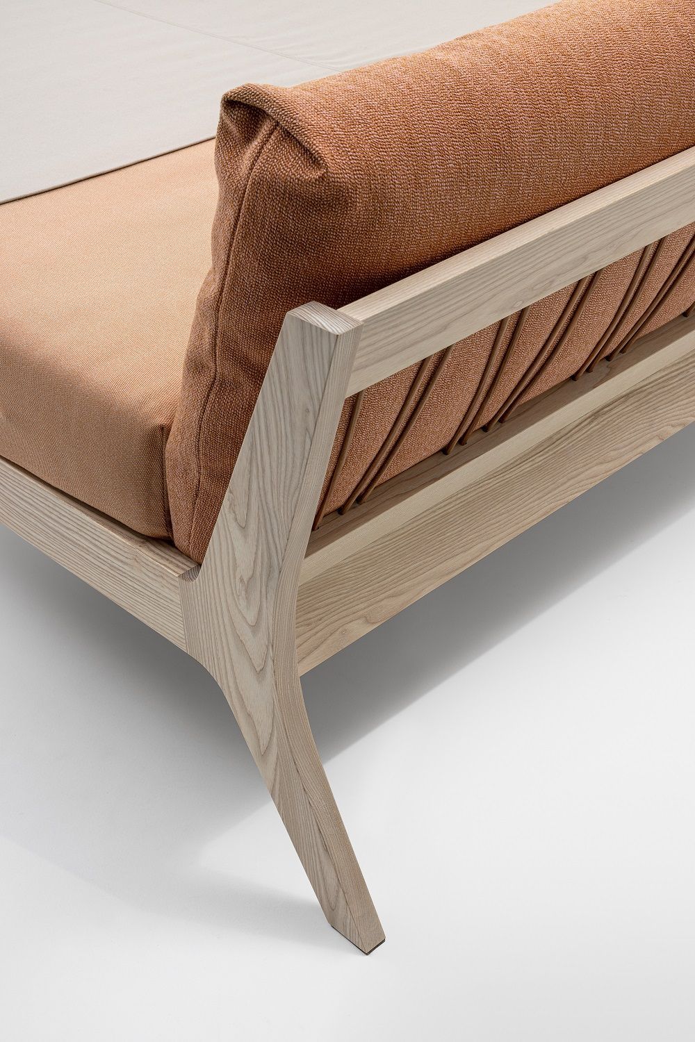 Detailaufnahme vom Mellow Bett Massivholz: Holzrahmen, orangefarbene Polsterung und modernes Design.