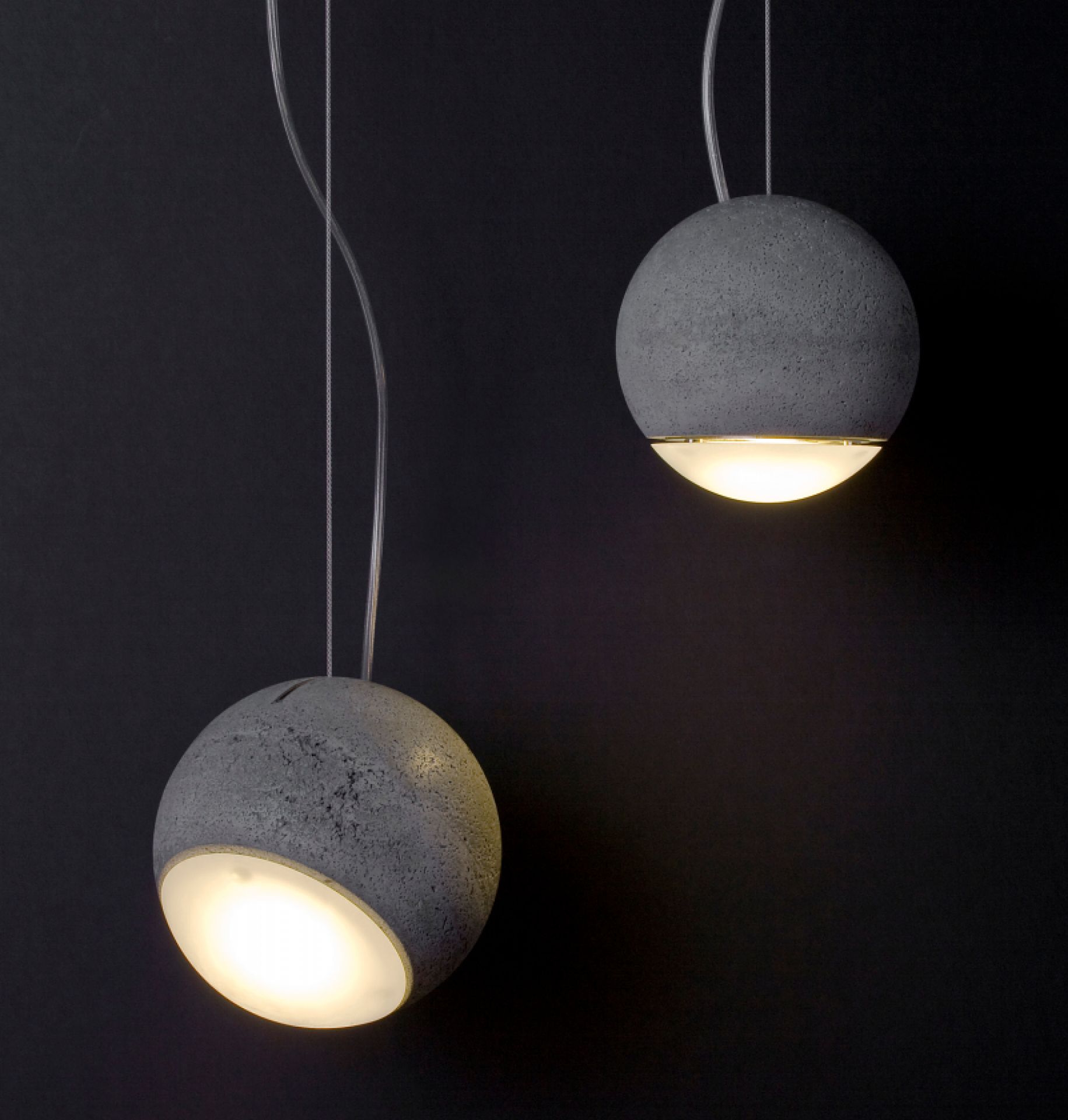 Zwei graue Trabant Pendelleuchten von Tecnolumen mit runder Form und warmweißem Licht vor dunklem Hintergrund.