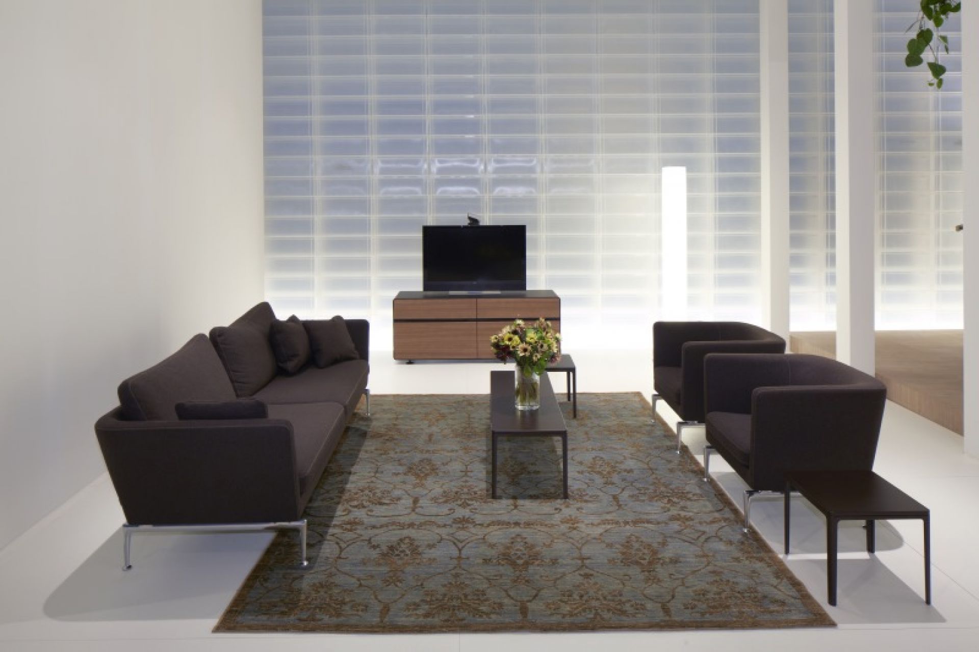 Wohnzimmer mit braunem Suita Club Sessel, Sofa, Teppich und TV-Möbeln in minimalistischem Design.