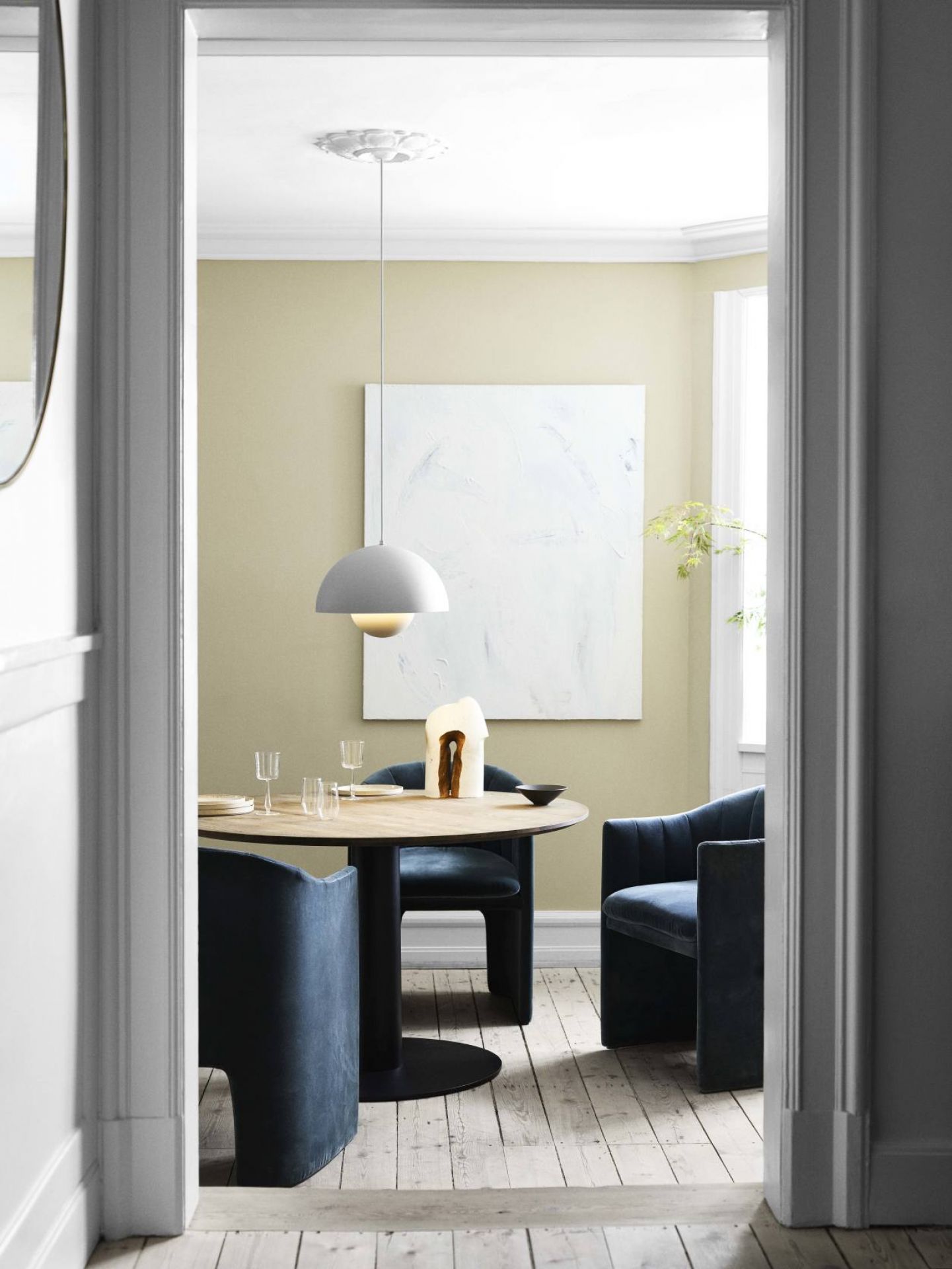 Esszimmer mit Loafer Sessel von AndTradition in blauem Samt und rundem Holztisch.