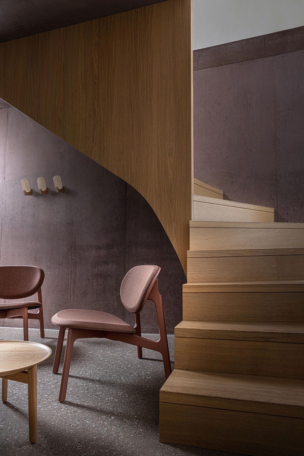 Ad Hook Wandhaken 3er Set aus Massivholz an einer Betonwand, neben einer Holztreppe.