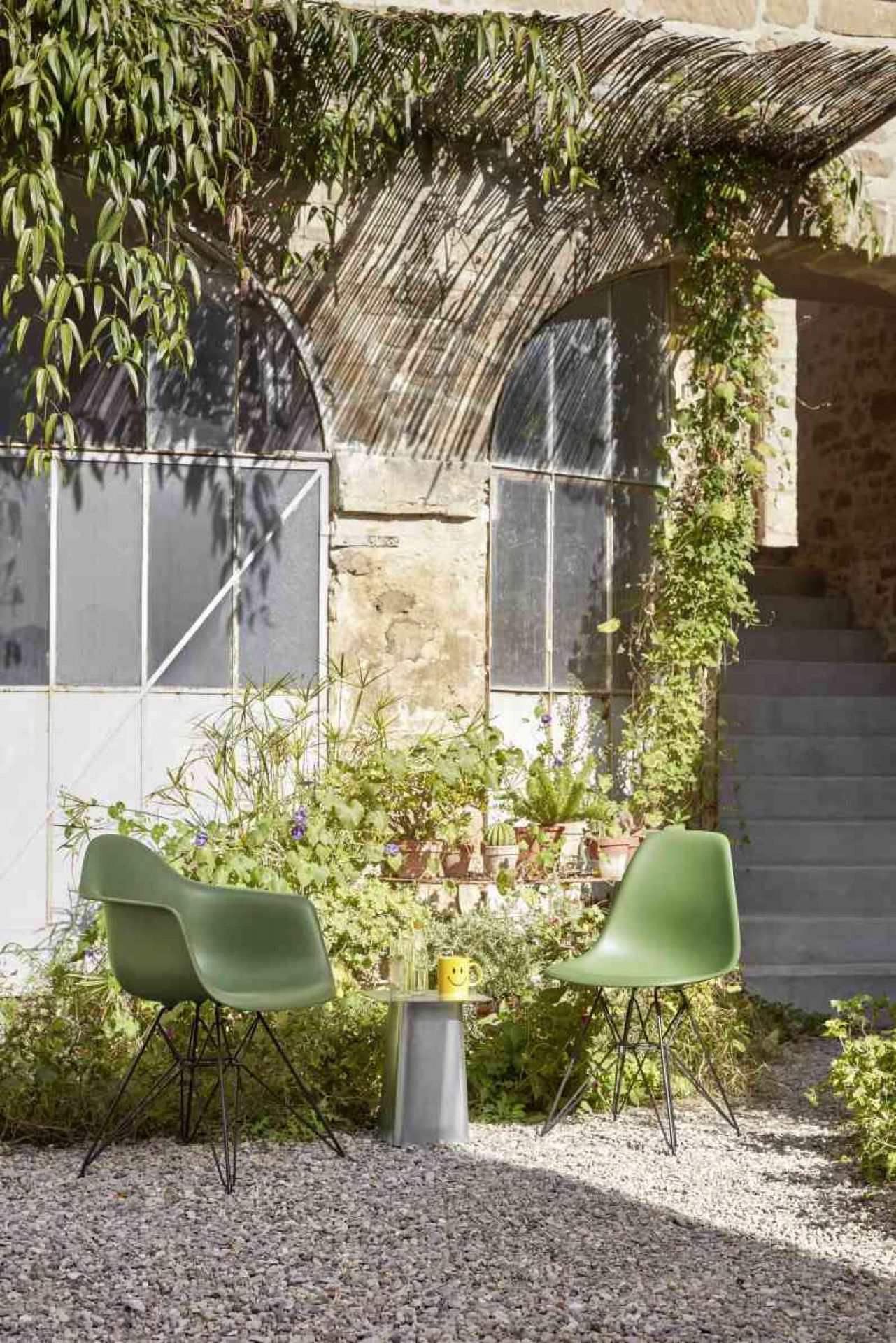 Vitra Beistelltisch Metal Side Table in Grau, Outdoor-geeignet, zwischen zwei grünen Stühlen.