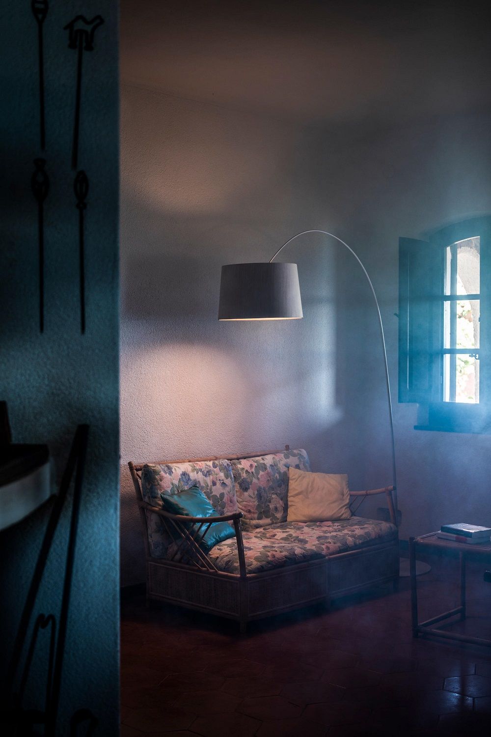 Graue Twiggy Elle Wood Stehleuchte von Foscarini beleuchtet stilvoll ein Wohnzimmer mit Sofa.