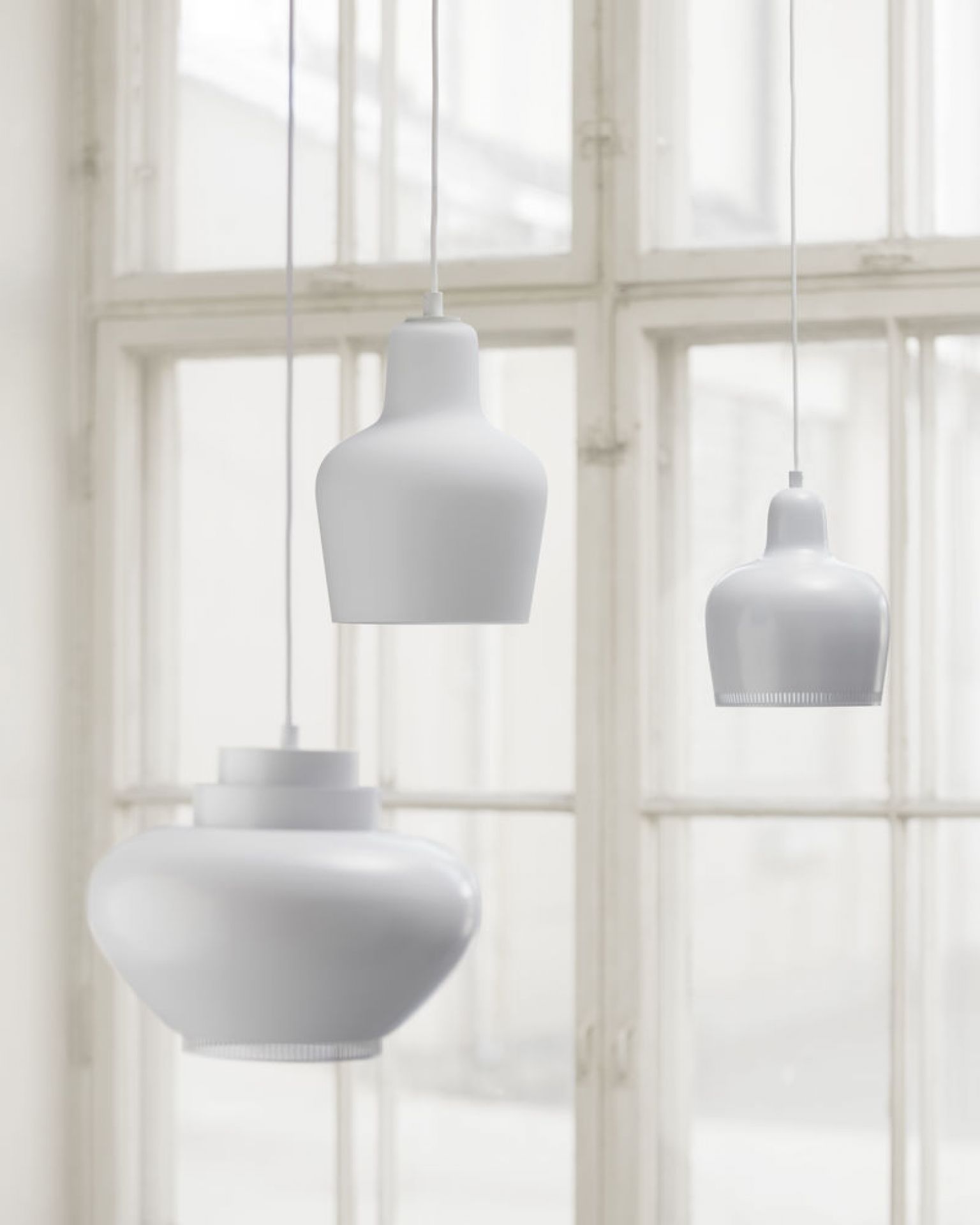 Drei weiße A333 Pendelleuchten Turnip Artek hängen vor einem Fenster. Moderne Hängelampen für Wohnzimmer.