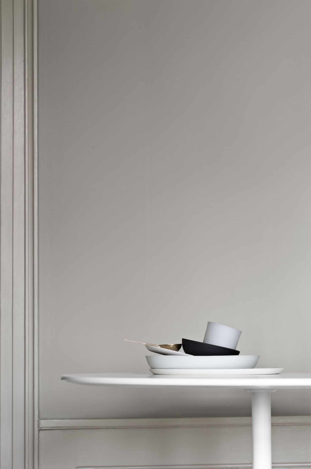 Weißer Panton Table Tisch von Montana mit Geschirr vor grauer Wand. Moderner Esstisch.