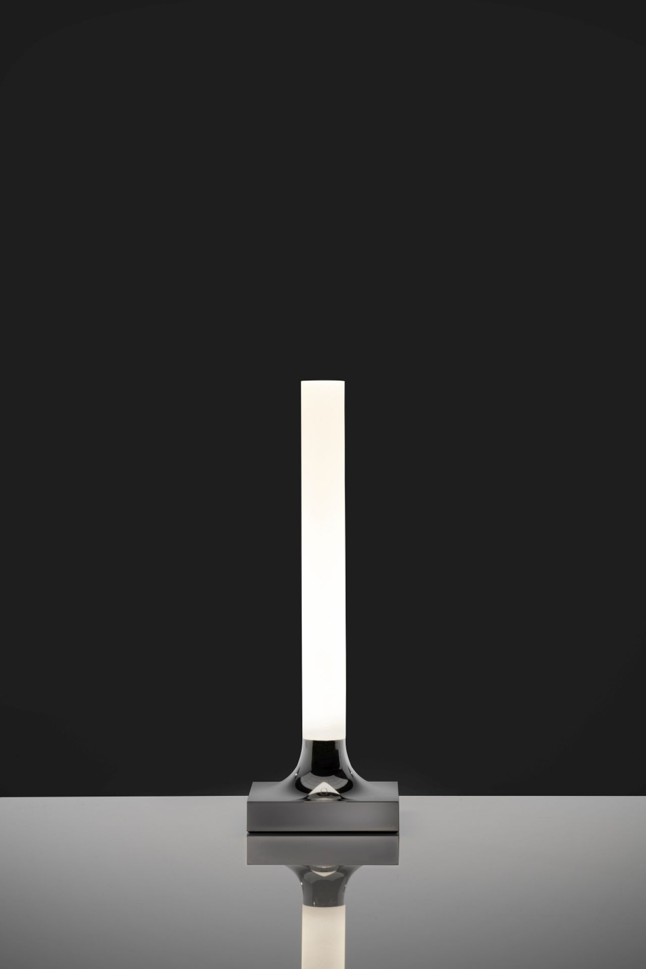 Goodnight Akkuleuchte von Kartell, verchromt und poliert, mit LED-Lichtstab auf glänzendem Untergrund.