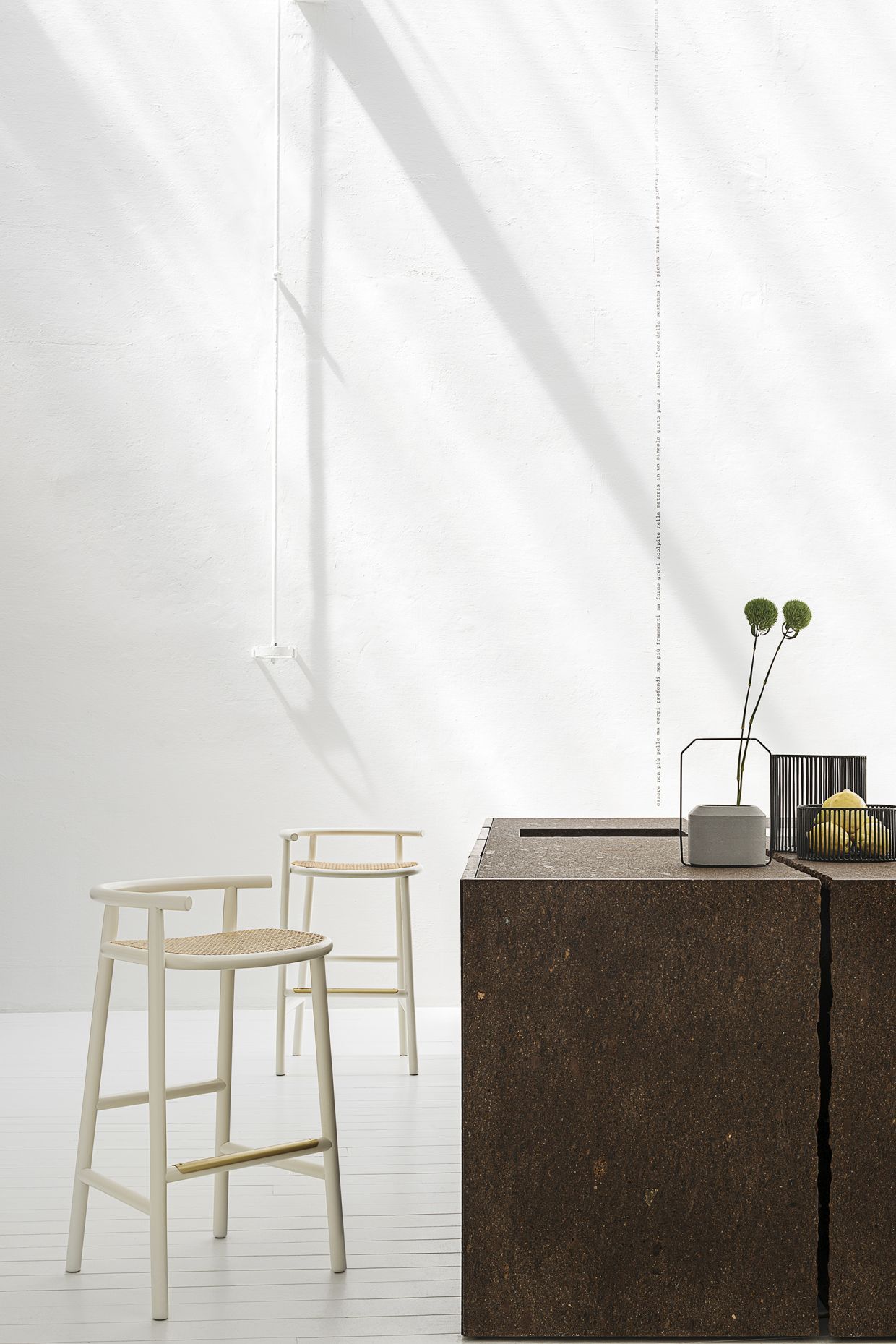 Zwei weiße Barhocker mit geflochtenen Sitzen von Wiener GTV Design vor minimalistischem Hintergrund.