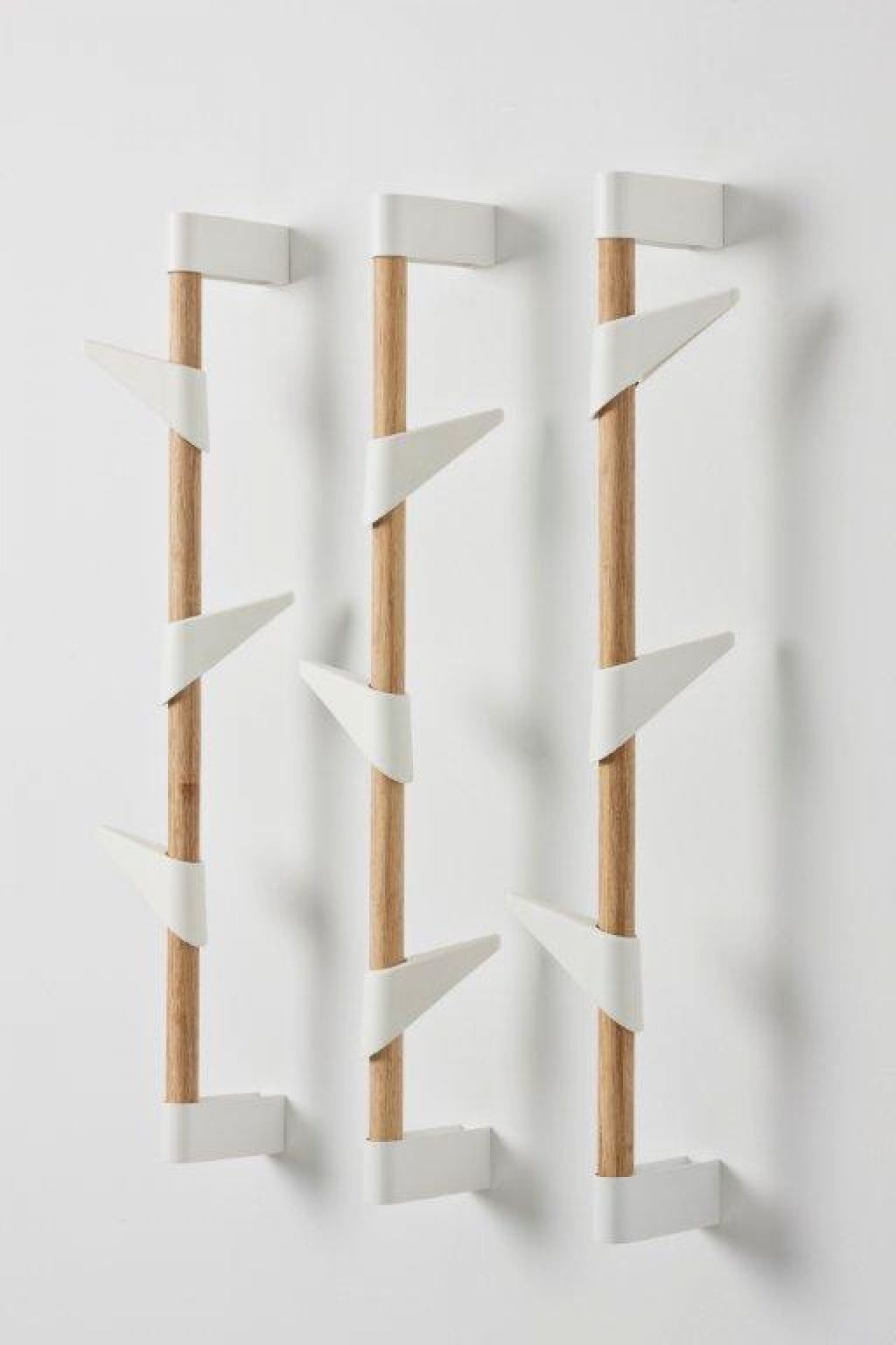 Drei Cascando Wandgarderoben aus Bambus mit weißen Haken an einer weißen Wand.