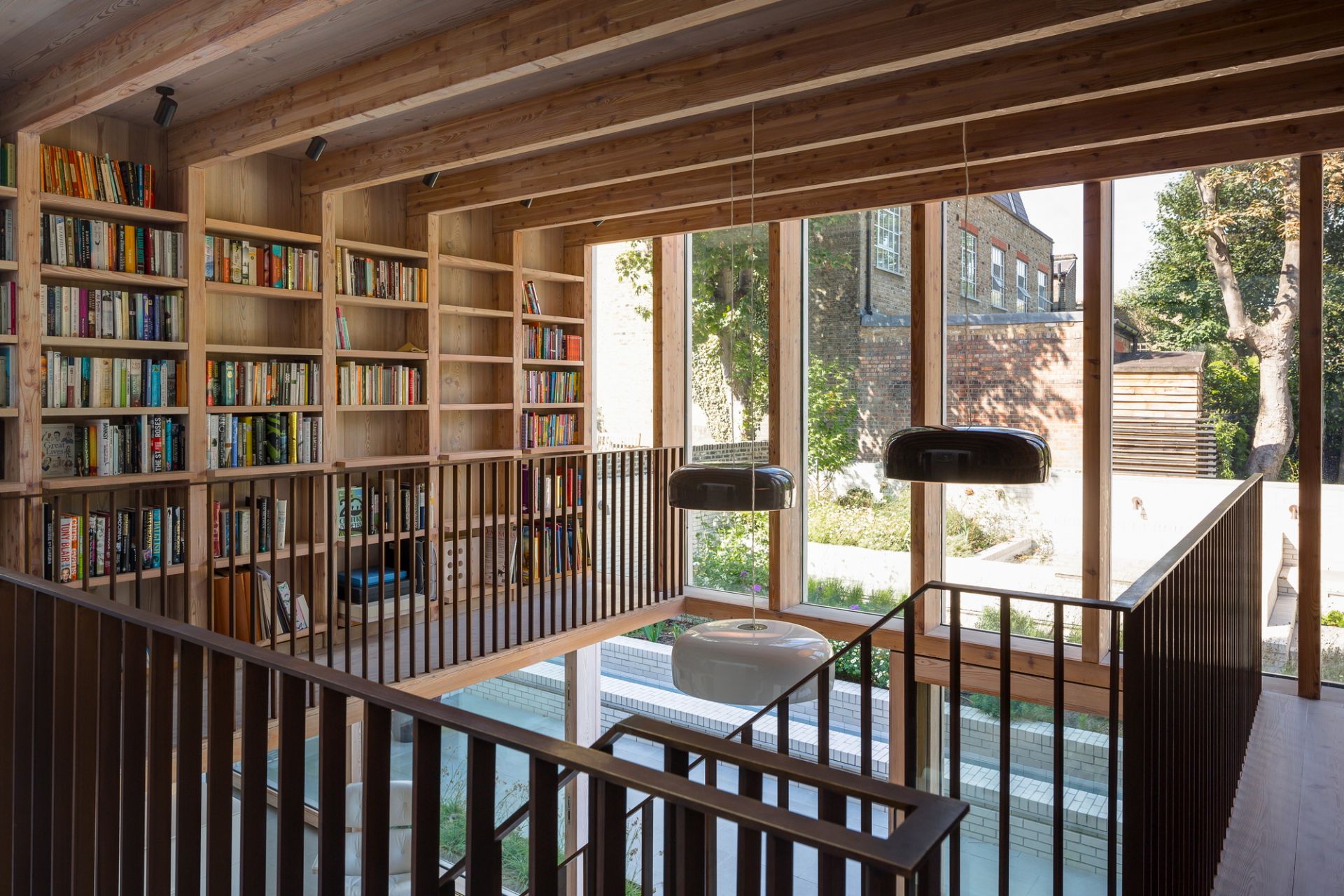 Innenaufnahme mit Smithfield Pendelleuchten von Flos in modernem Wohnraum mit Bücherregal.