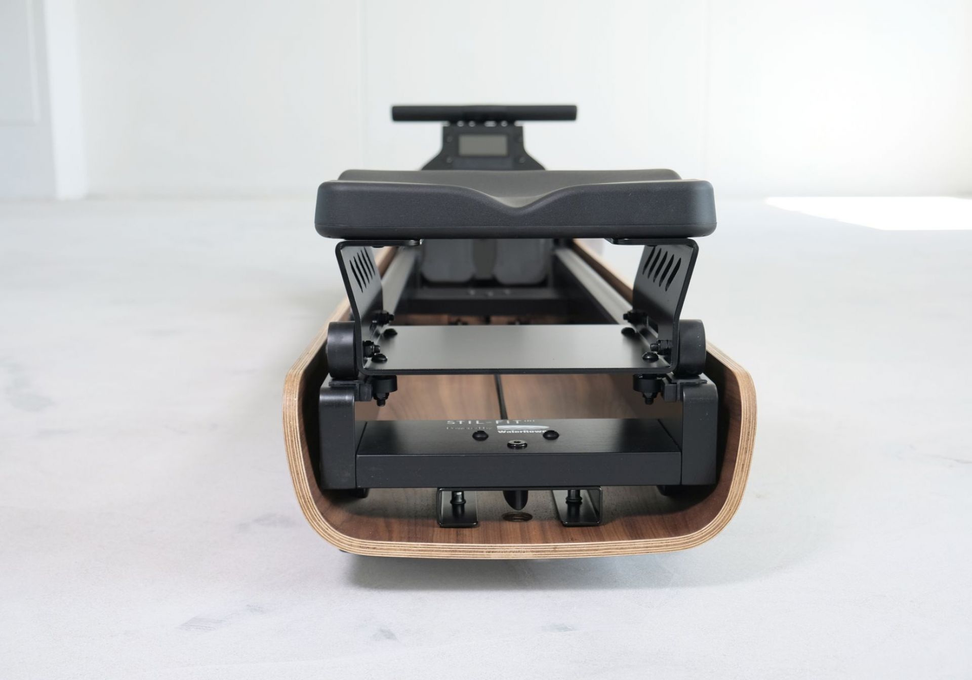 Detailaufnahme des FLOW ONE Rudergeräts von Stil-Fit mit edlem Walnuss-Holzrahmen und schwarzem Sitz.