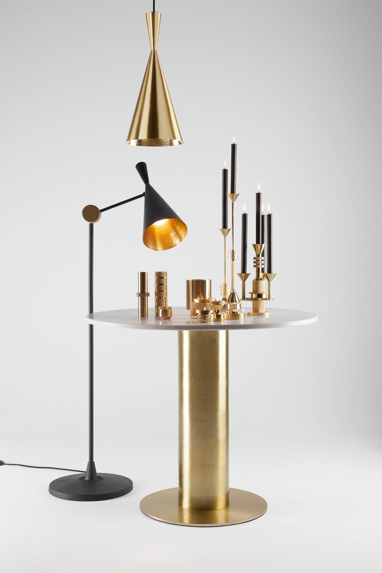 Beat Stehleuchte von Tom Dixon, schwarzer Lampenschirm mit goldener Innenseite, auf Tisch mit Kerzen.