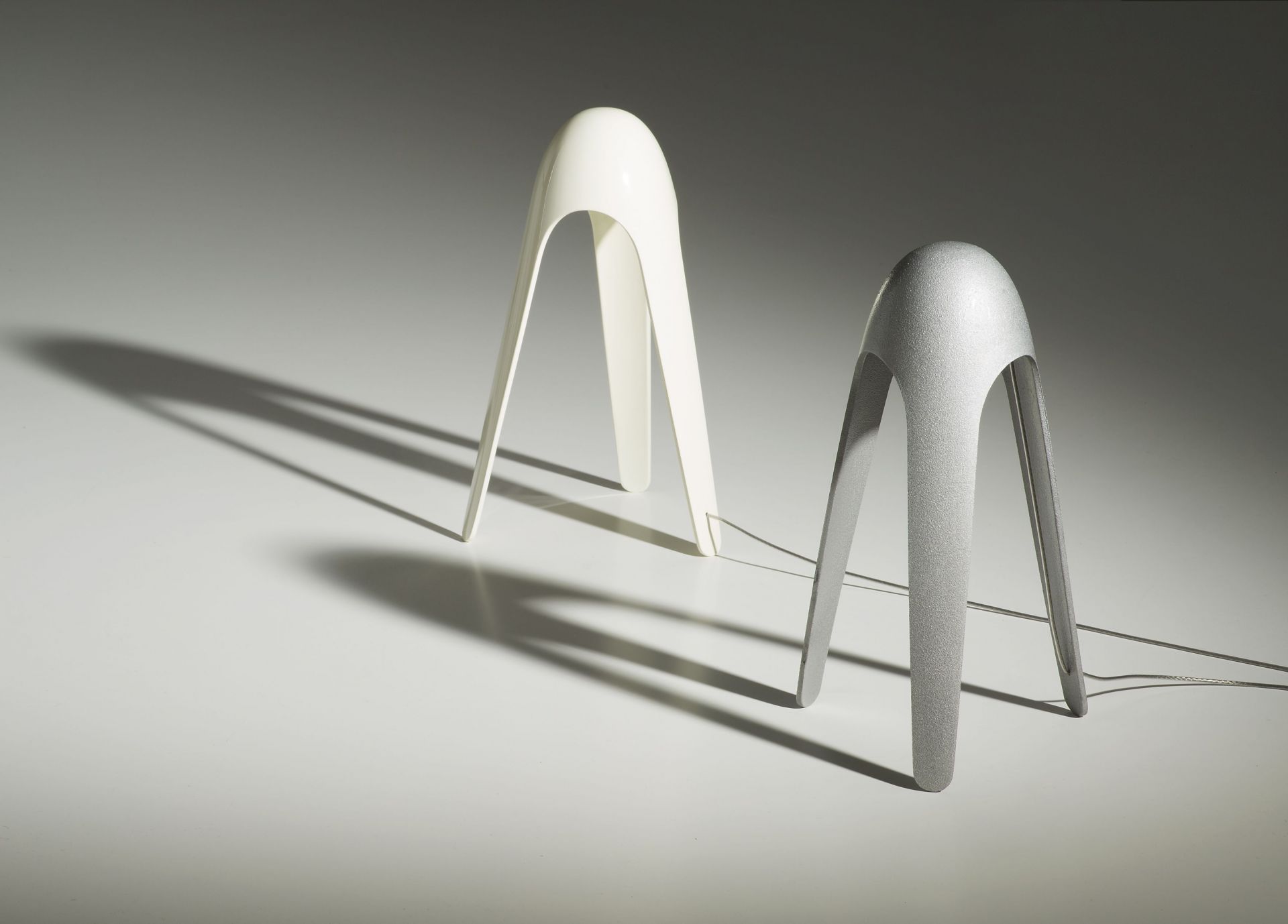 Zwei Cyborg Tischleuchten von Martinelli Luce in Weiß und Silber auf hellem Untergrund.