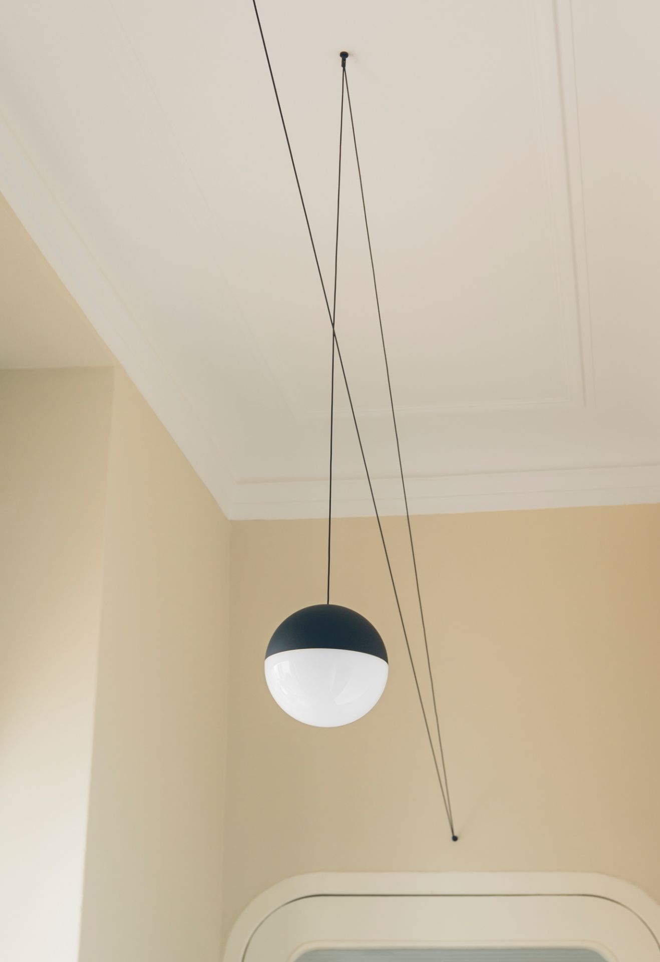 Nahaufnahme der String Light Kugelkopf Pendelleuchte von Flos mit schwarzem Kabel.