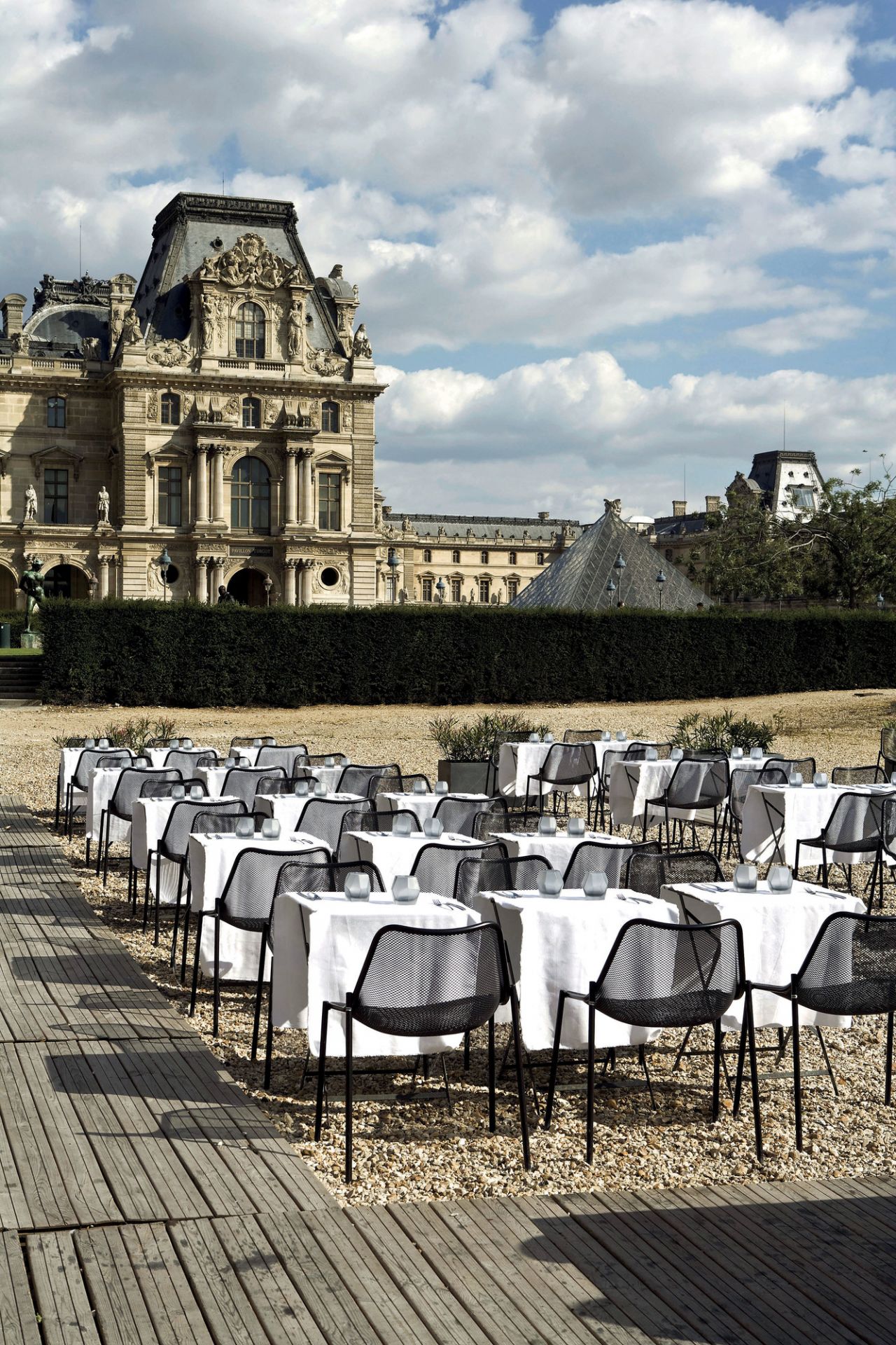 Viele schwarze Emu Round Stühle an Tischen im Freien vor historischem Gebäude. Gartenmöbel für Gastronomie.