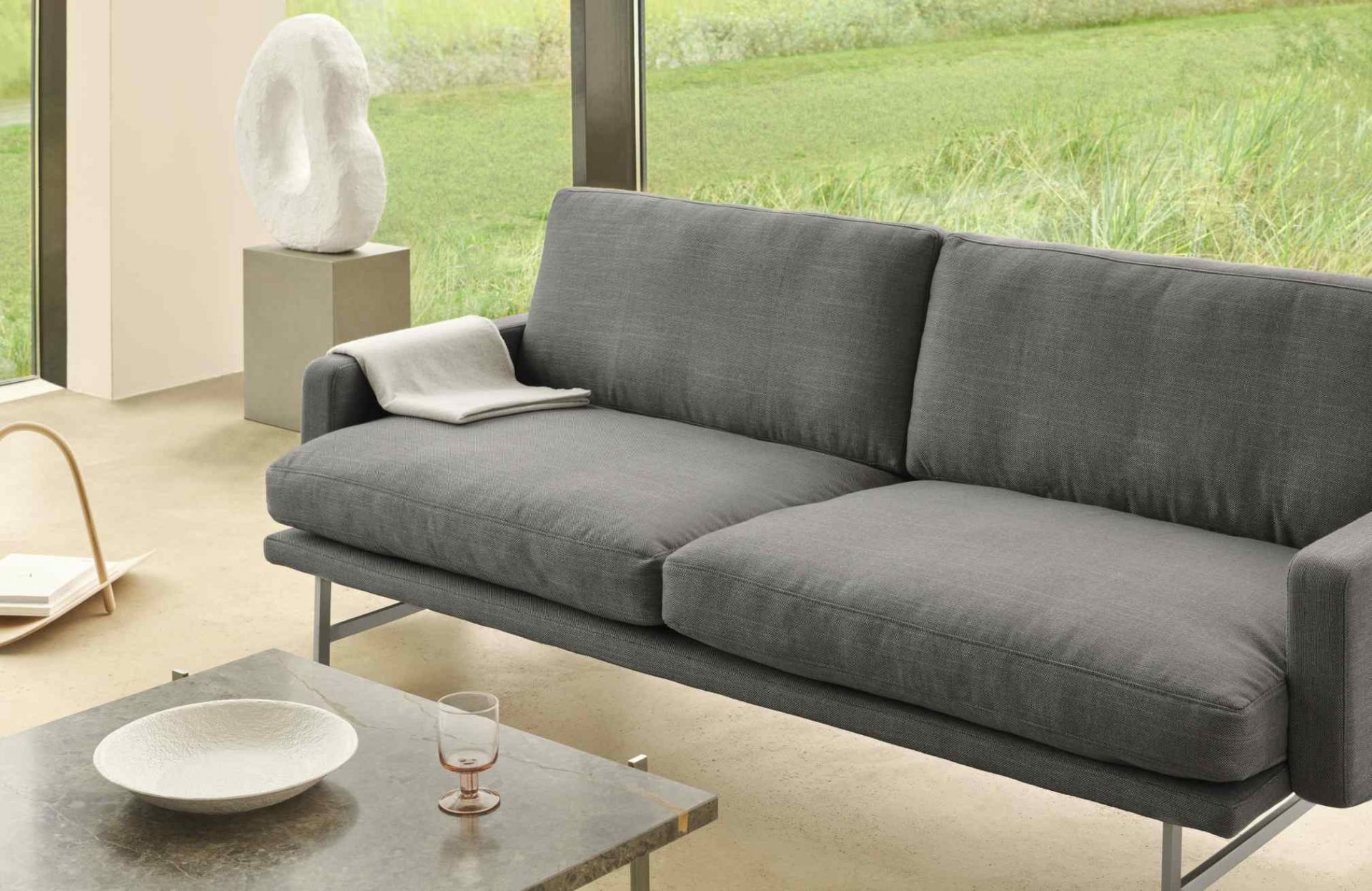 Graue Couch mit PK 61 Couchtisch von Fritz Hansen im modernen Wohnzimmer.