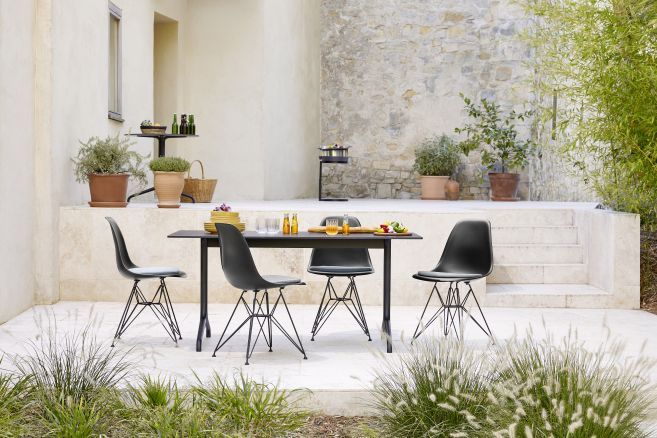 Schwarze Stühle mit Vitra Soft Seats Sitzkissen an einem Esstisch im Freien. Outdoor Möbel.