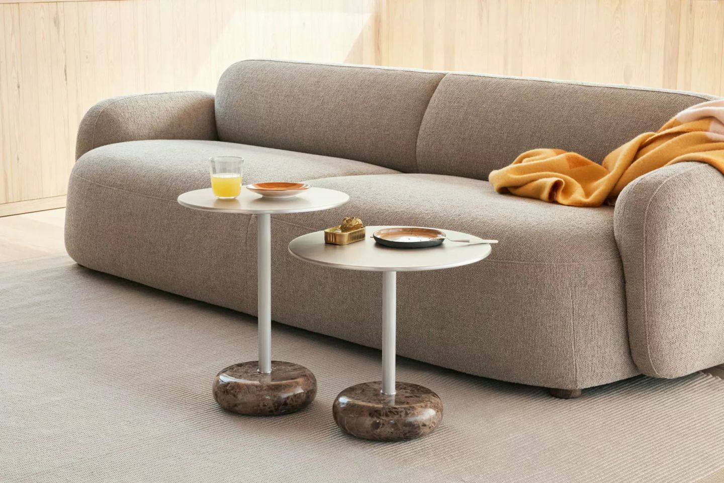 Zwei Northern Ton Beistelltische mit Marmorfuß und Getränken vor einem grauen Sofa im Wohnzimmer.
