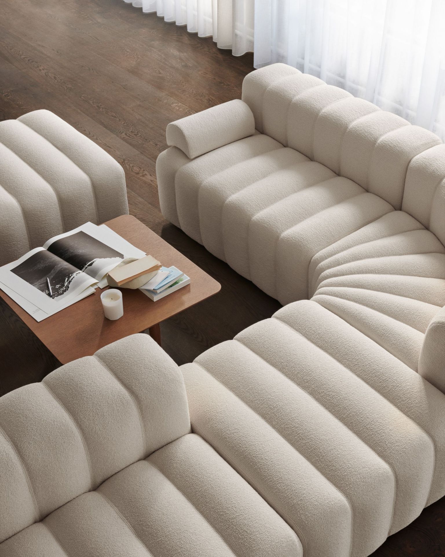 Oku Couchtisch Eiche hell geräuchert von Norr11 neben einem modularen Sofa in hellem Bouclé.