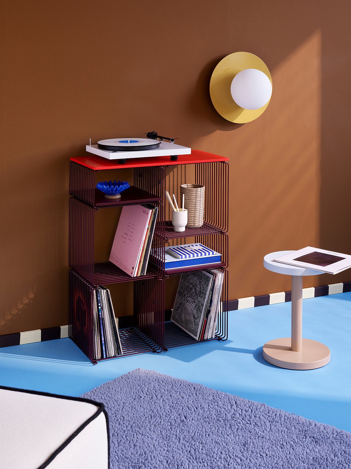 Regalsystem mit Panton Wire Elementen und roter Abdeckplatte von Montana, gefüllt mit Schallplatten und Deko.