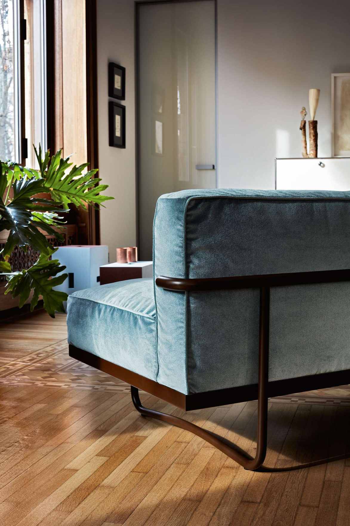 Detailaufnahme des LC5 Canapé Sofa von Cassina mit blauem Bezug und dunklem Holzrahmen.