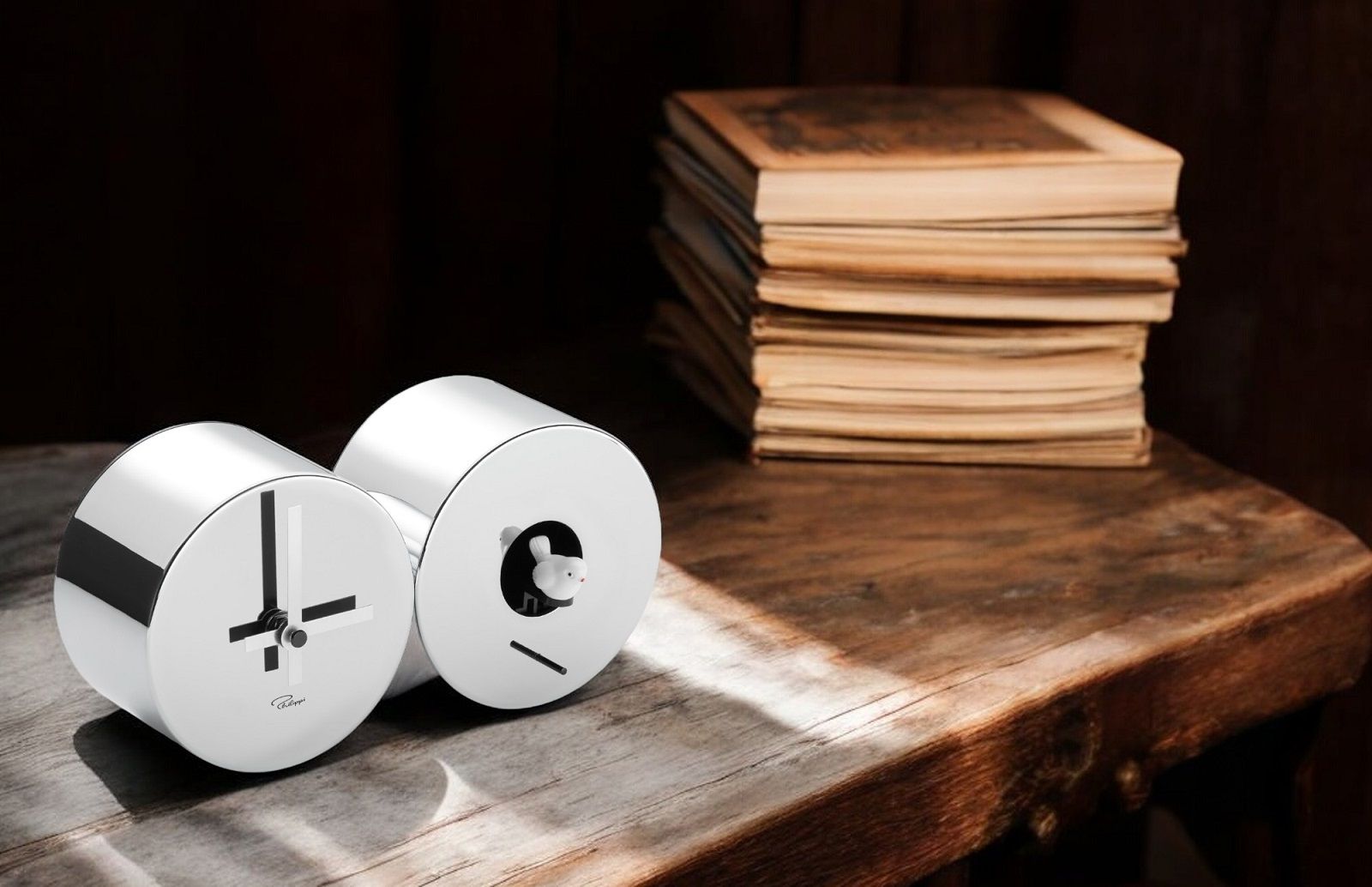 CUCULO Kuckucksuhr von Philippi, moderne Tischuhr mit Kuckuck, silberfarben, auf einem Holztisch mit Büchern.