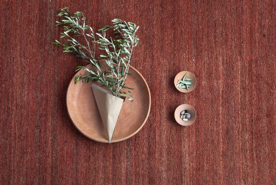 Nanimarquina Earth Rug Teppich Khaki 250x350cm, Detailansicht mit Olivenzweig und Dekoration. Hochwertiger Teppich für Wohnräume.