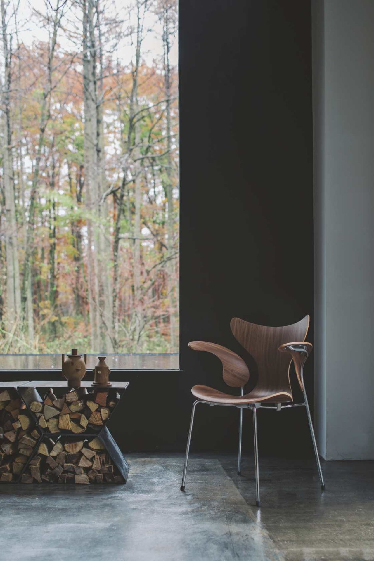 Fritz Hansen Lily Armlehnenstuhl 3208 aus Holz mit Stahlbeinen vor Fenster. Designklassiker.