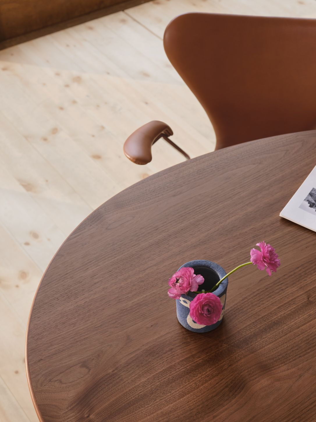 Detailaufnahme des Fritz Hansen Egg Table Tisches aus Holz mit Blumen und Stuhl.