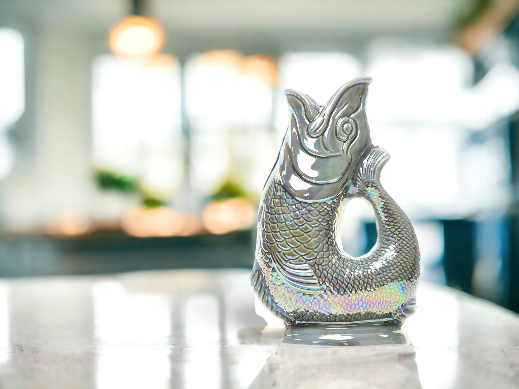 Silberne Gluckigluck Fischkaraffe mit schimmernden Schuppen auf einer Marmoroberfläche, dekorative Wasserkaraffe.