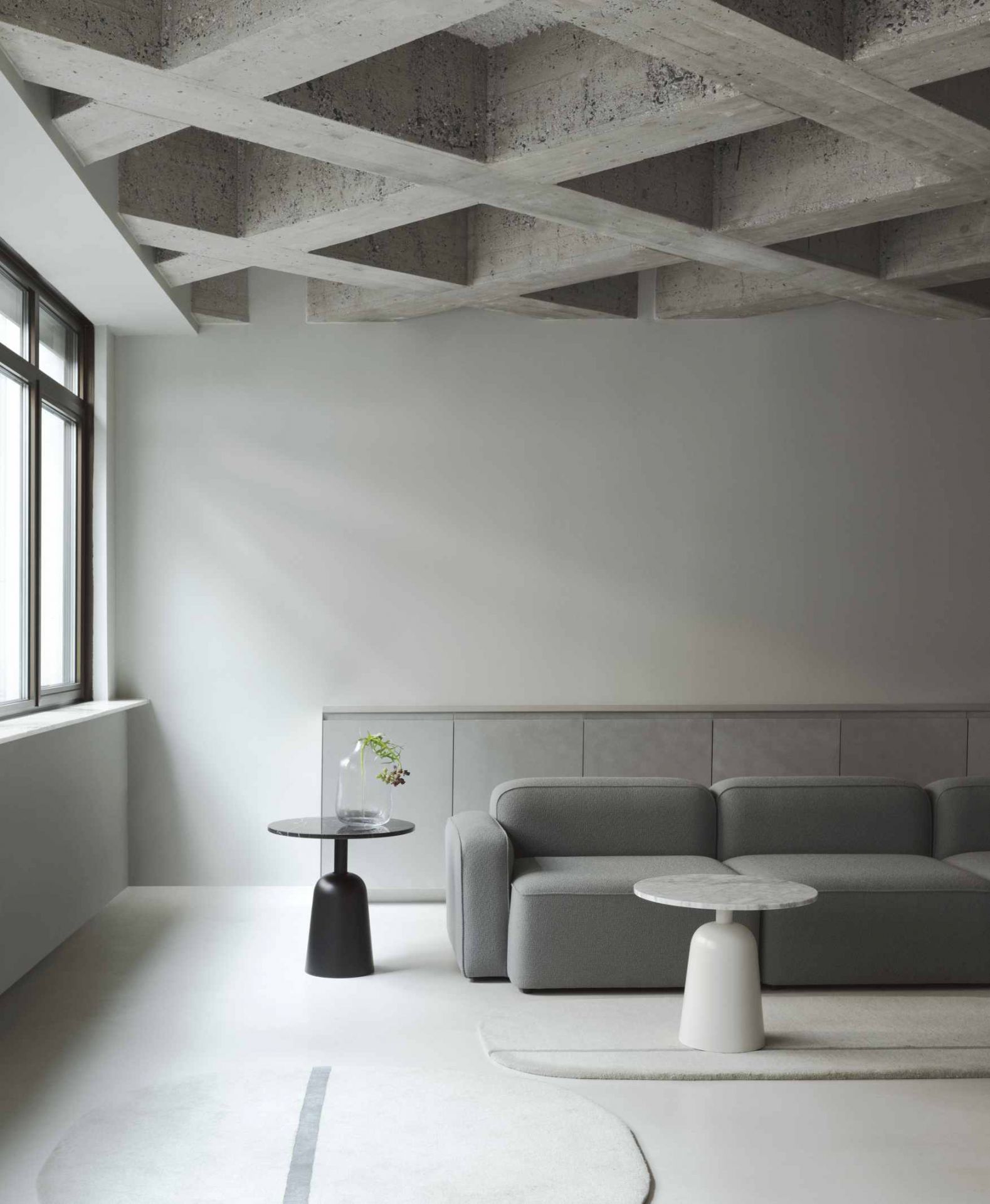 Minimalistisches Wohnzimmer mit grauem Sofa und zwei Beistelltischen, darunter ein Turn Table Marmor Tisch von Normann Copenhagen.