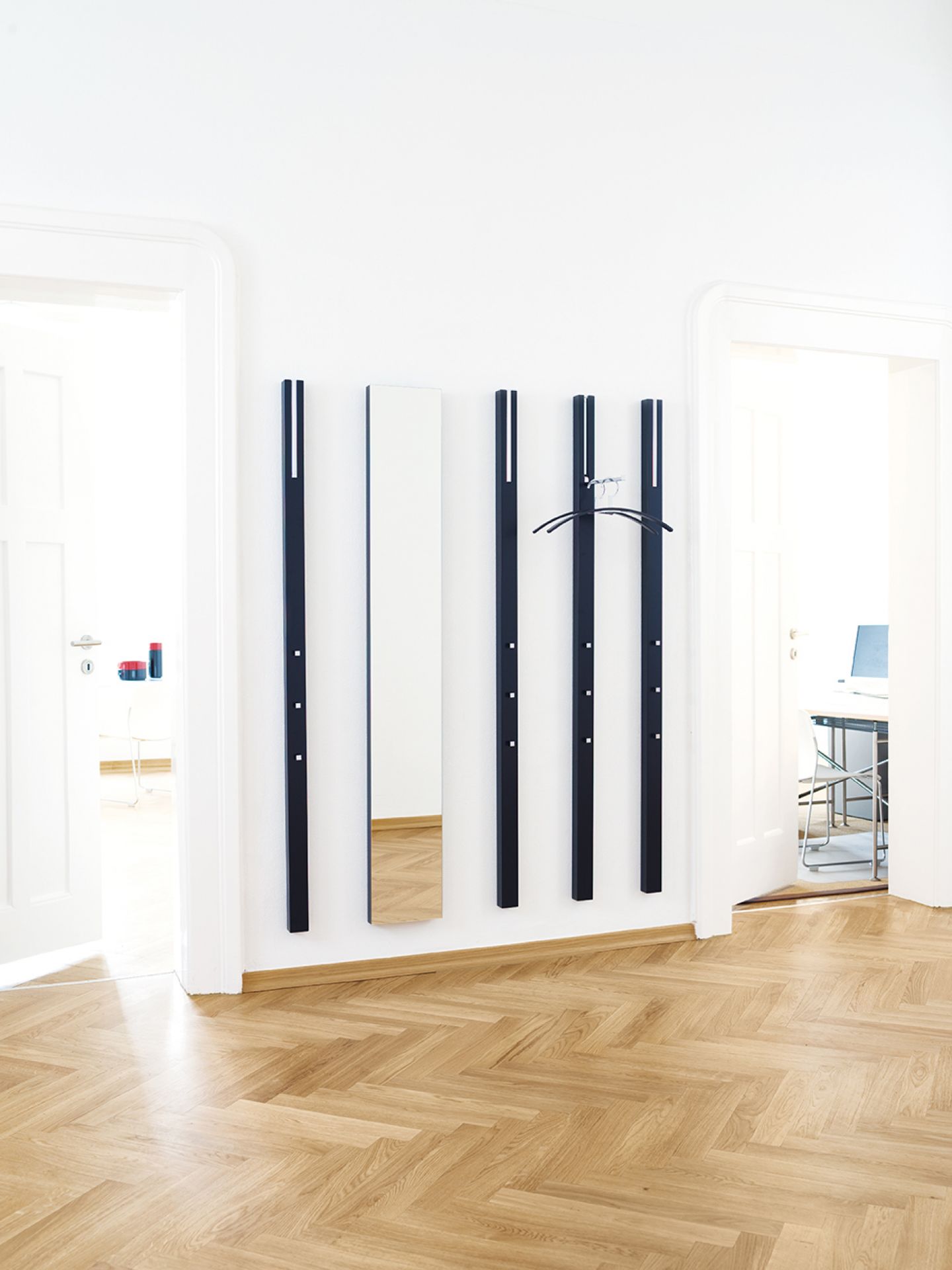 Schönbuch Line Spiegel und Garderobenelemente in Schwarz an weißer Wand über Parkettboden. Moderner Flurspiegel und Garderobe.