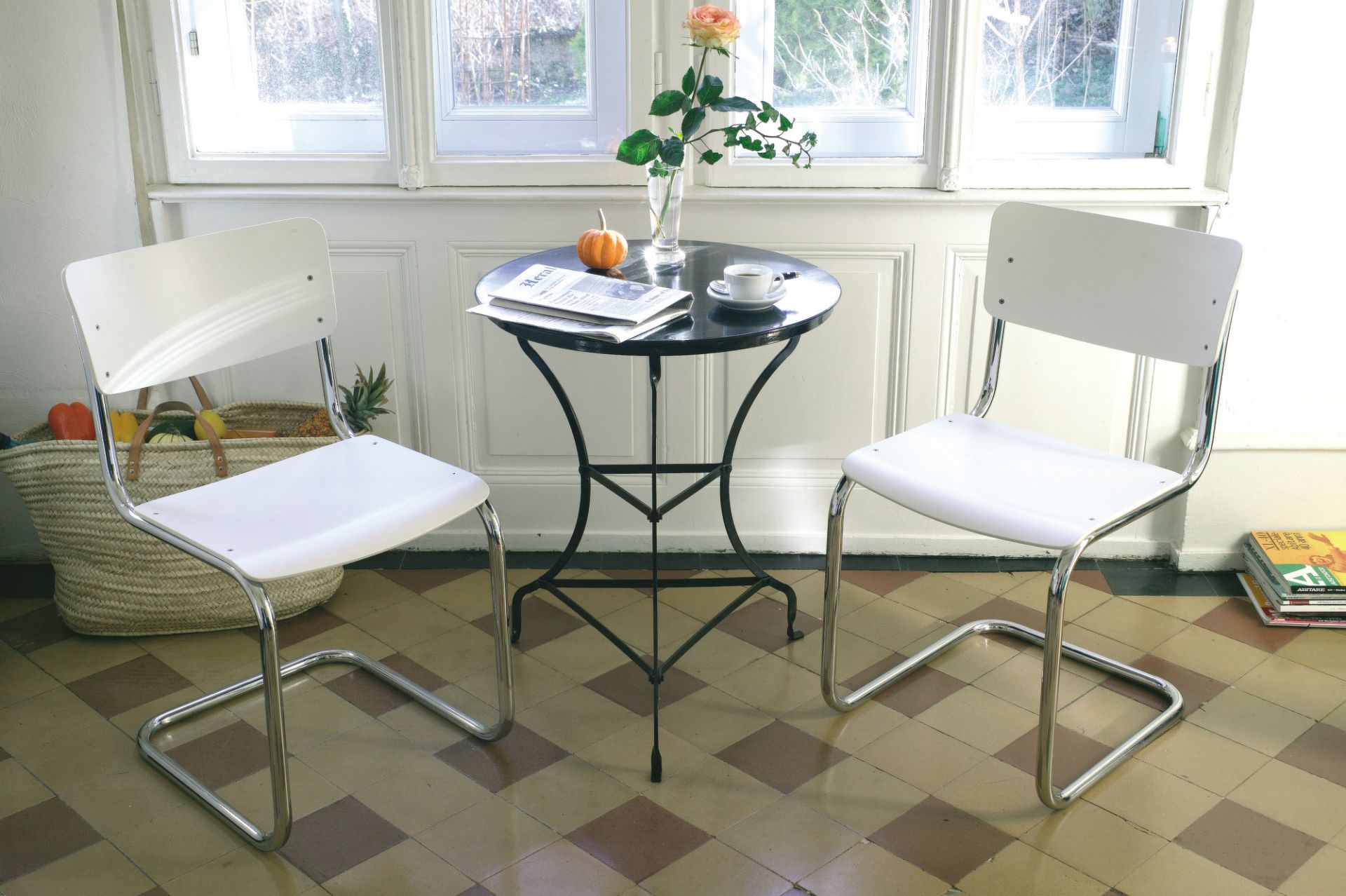 Zwei weiße S 43 Freischwinger Stühle von Thonet mit Stahlrohr Gestell an einem Tisch.