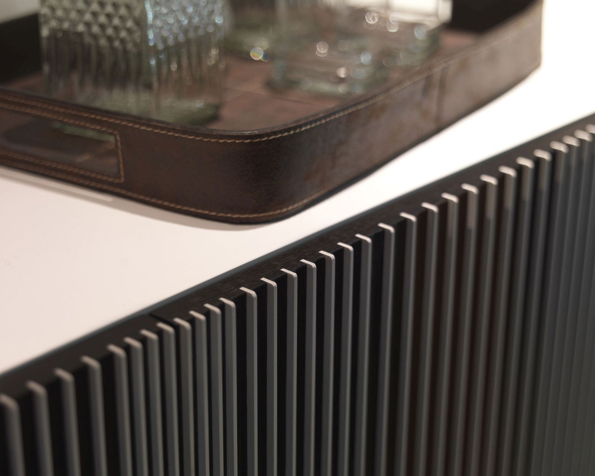 Detailaufnahme der Carlos Anrichte mit geriffelter Front und Leder-Tablett mit Gläsern.