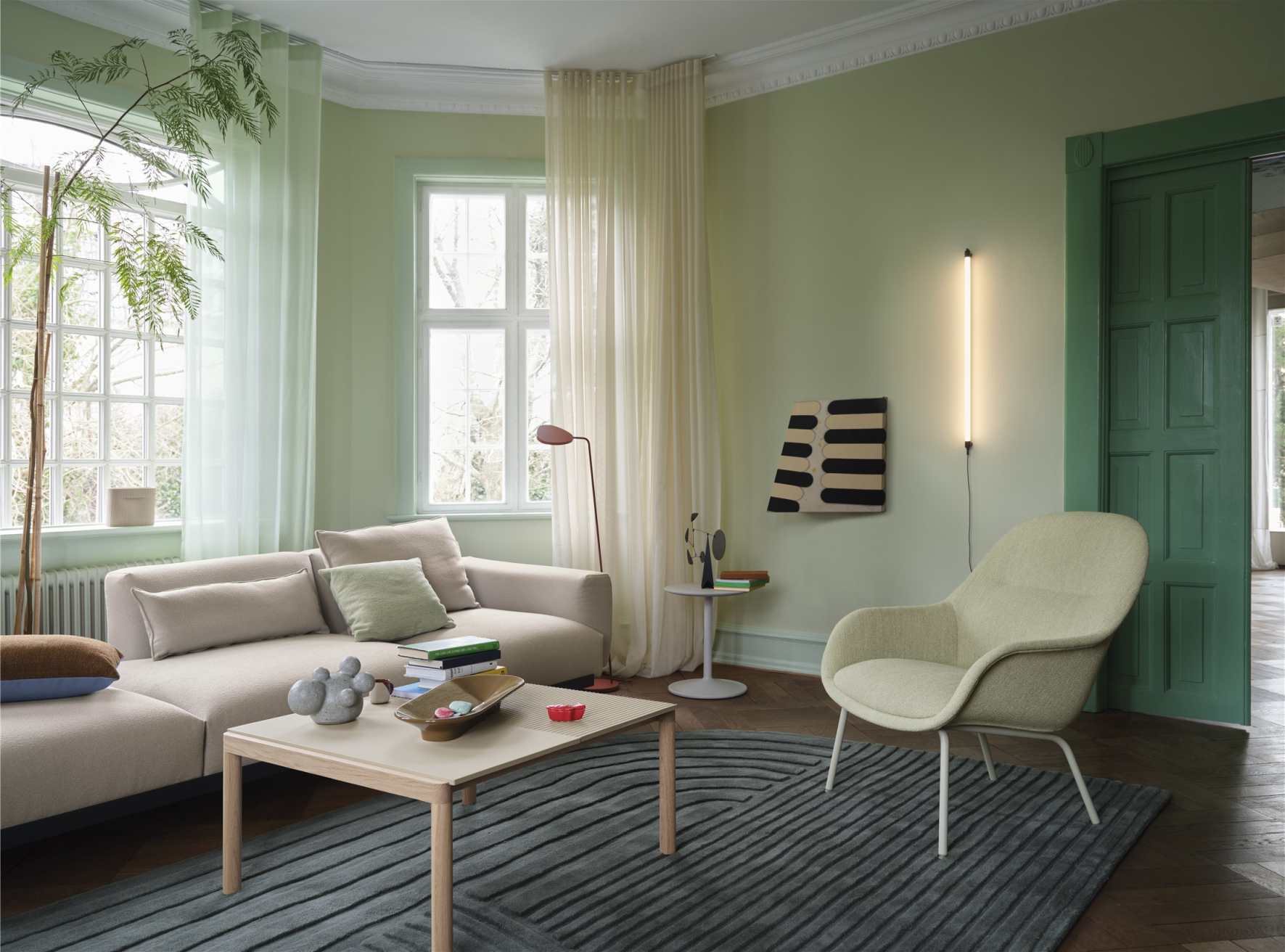 Wohnzimmer mit Fine Wall Wandleuchte von Muuto, die vertikal an der Wand montiert ist.