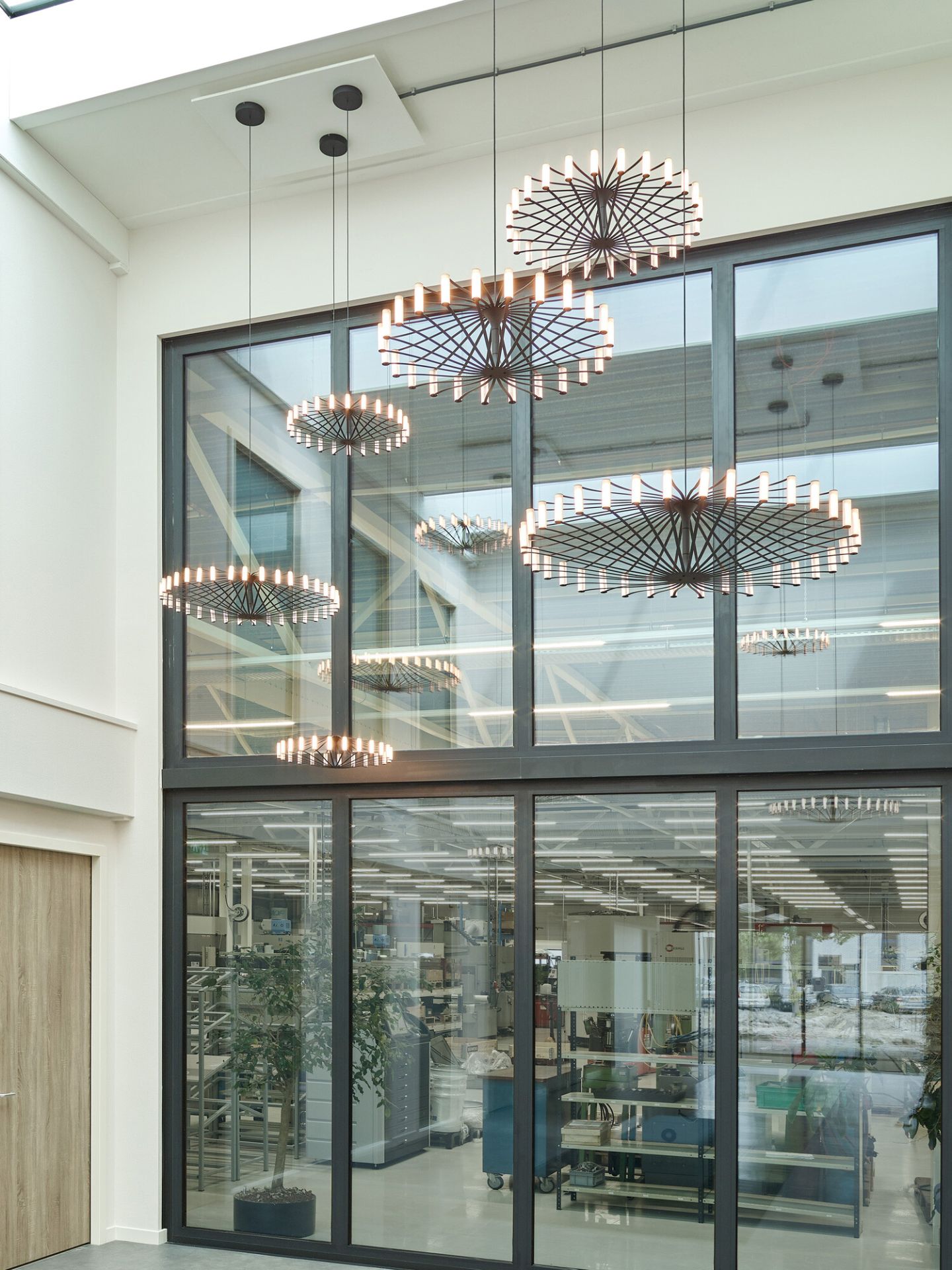 Mehrere Wheel Pendelleuchten Japth hängen in einem modernen Büro vor einer großen Fensterfront.