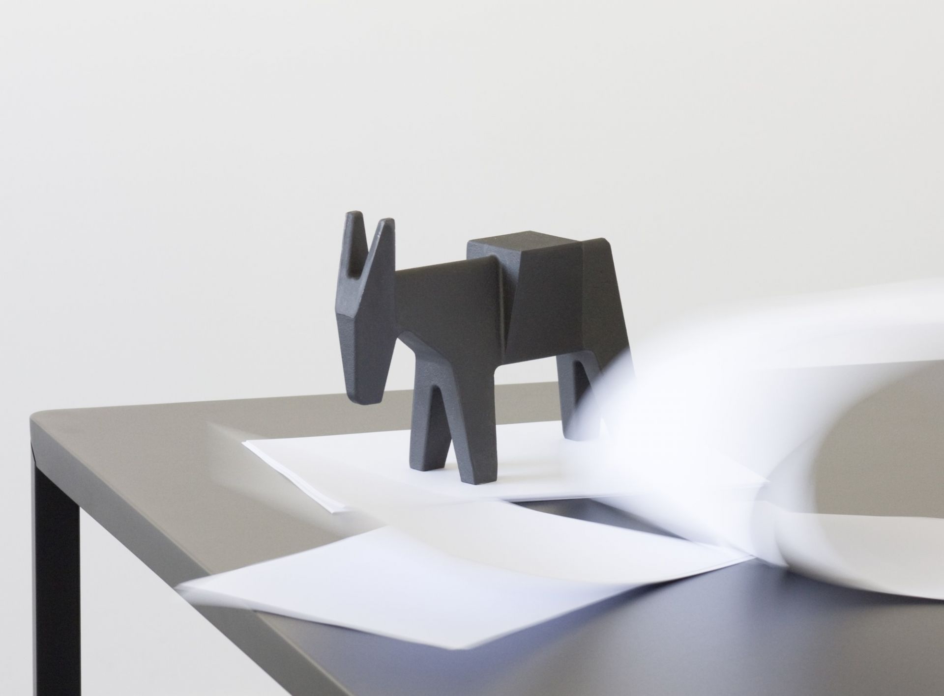 Schwarzer Ettore Türstopper in Eselform von Magis auf einem Tisch mit Papier. Design Türstopper.
