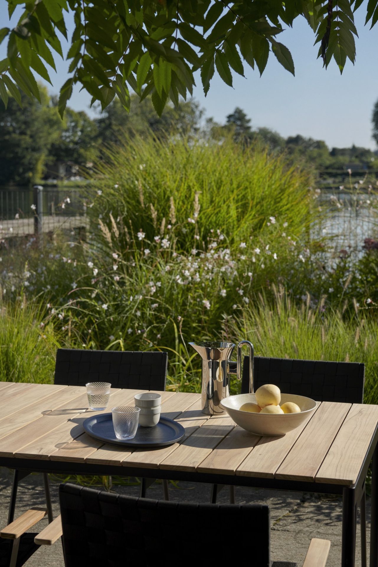 AndTradition Ville AV34 Outdoor Chair mit Esstisch und Dekoration im Garten.