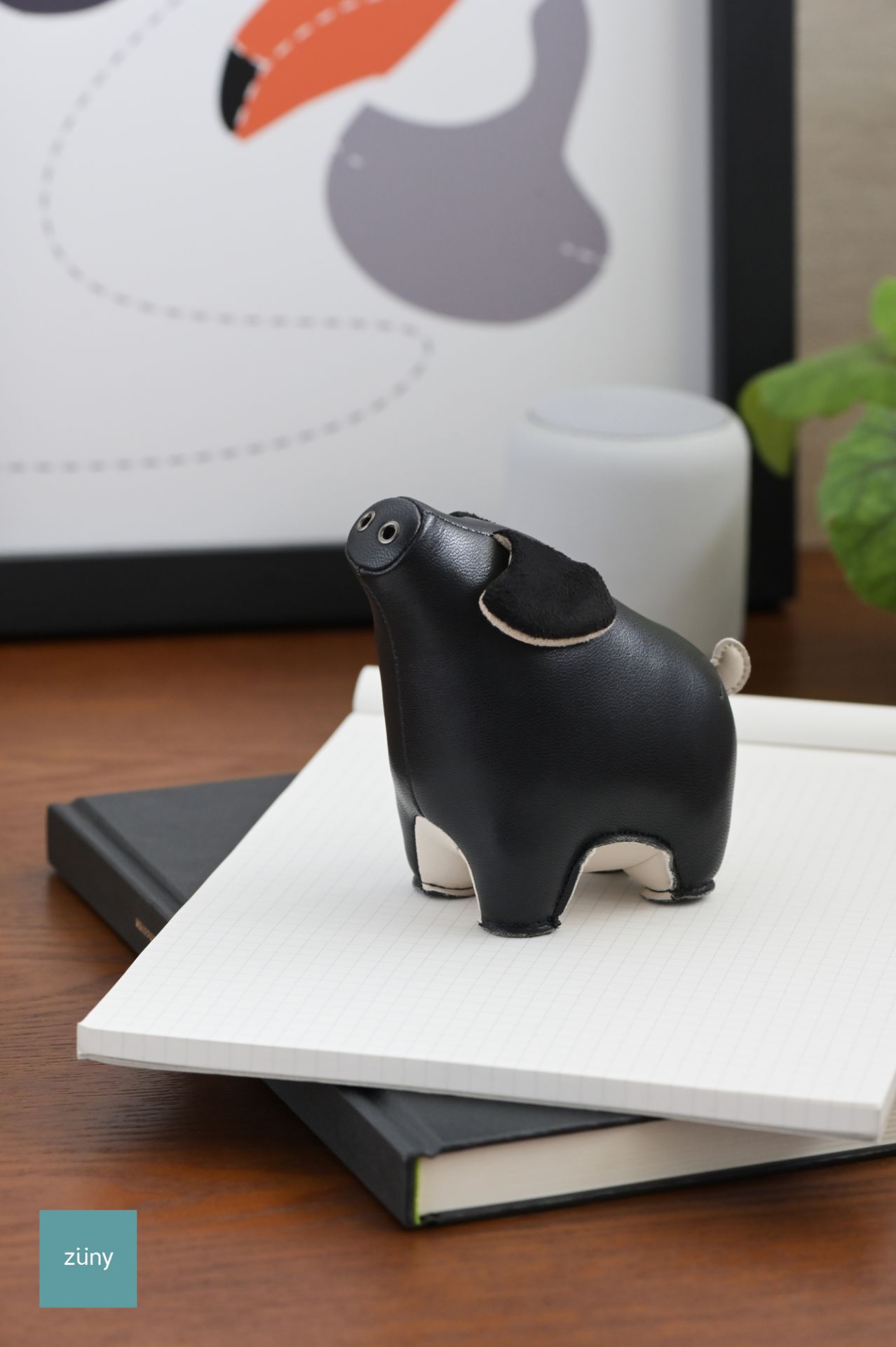 Schwarzer Züny Briefbeschwerer in Schweinchenform auf einem Notizbuch, dekoratives Accessoire für Büro und Schreibtisch.