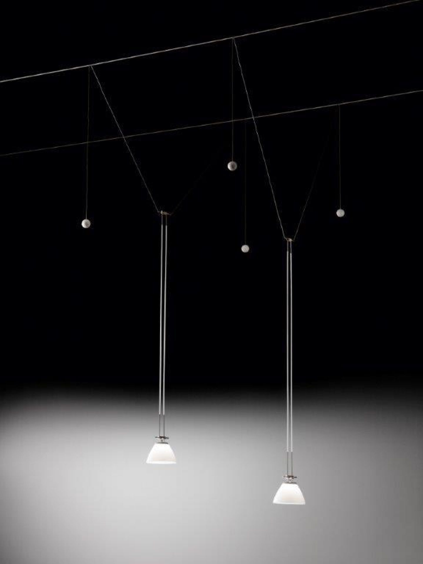 YAYAHO Lichtsystem von Ingo Maurer mit zwei Hängelampen und fünf Reflektoren vor schwarzem Hintergrund.